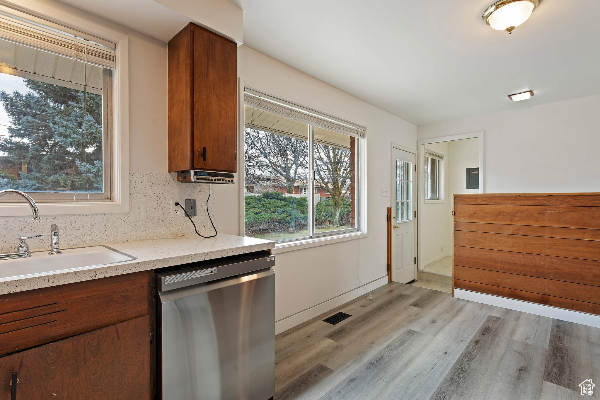 Kitchen with backsplash, dishwasher, light hardwood / wood-style floors, and sink