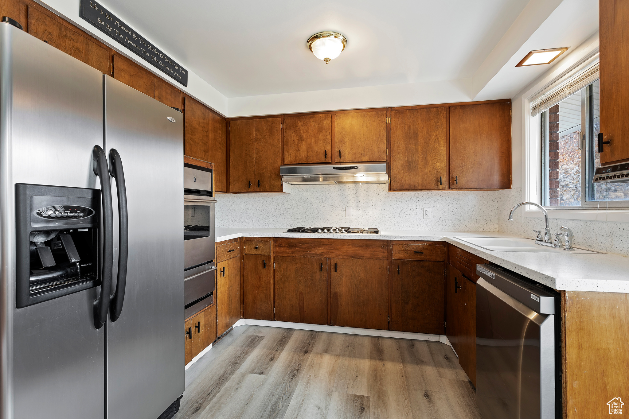 Kitchen featuring backsplash, sink, light wood-type flooring, and stainless steel appliances