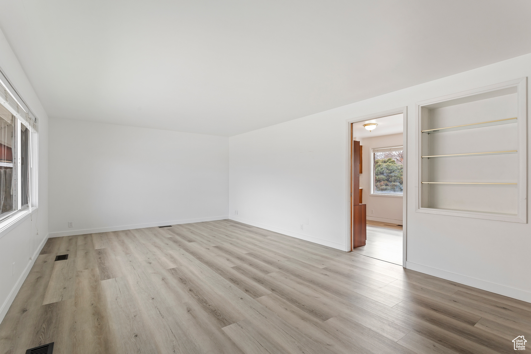 Empty room featuring built in shelves and light hardwood / wood-style floors