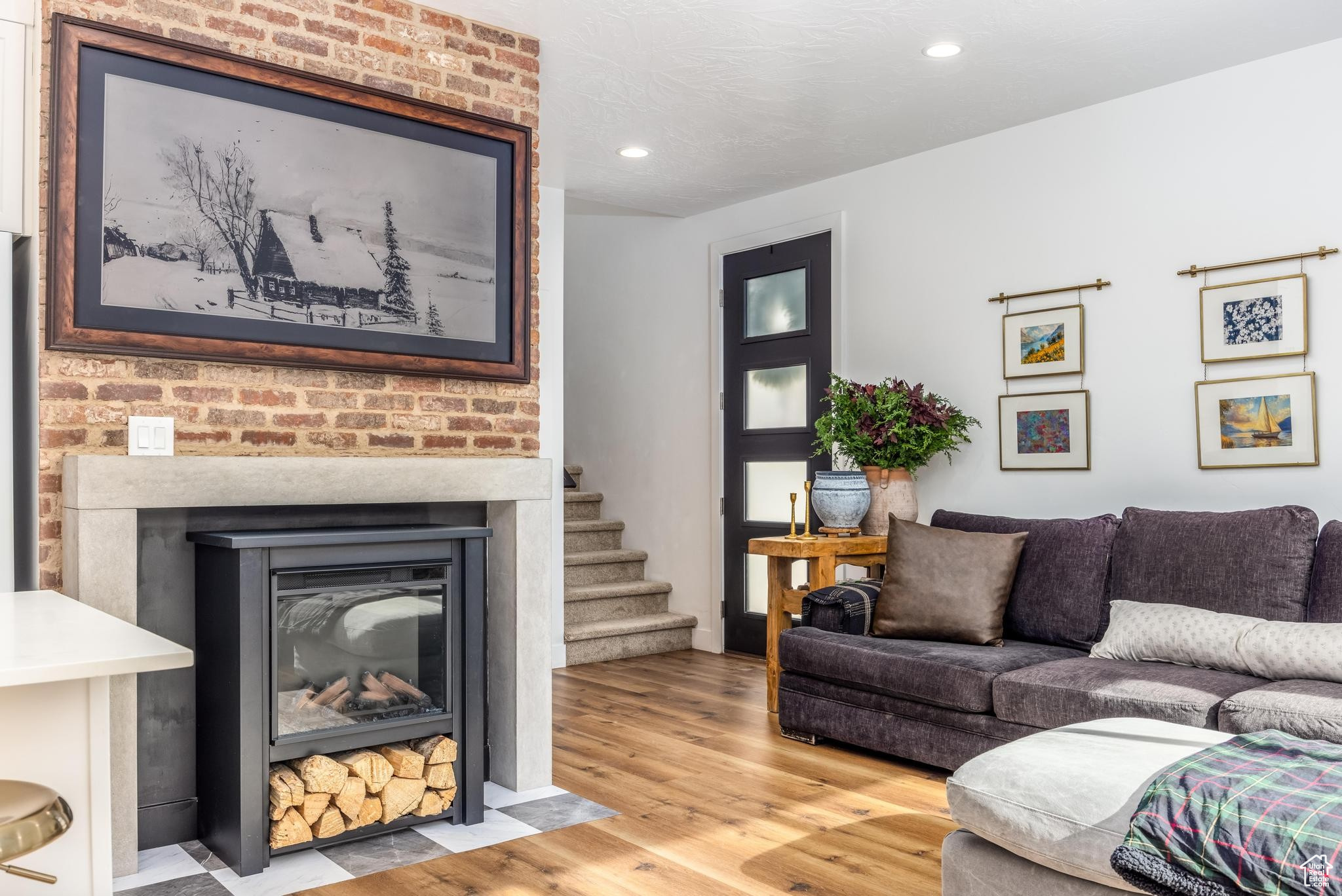 Living room hardwired for picture TV, with hardwood / wood-style floors and a brick designed fireplace