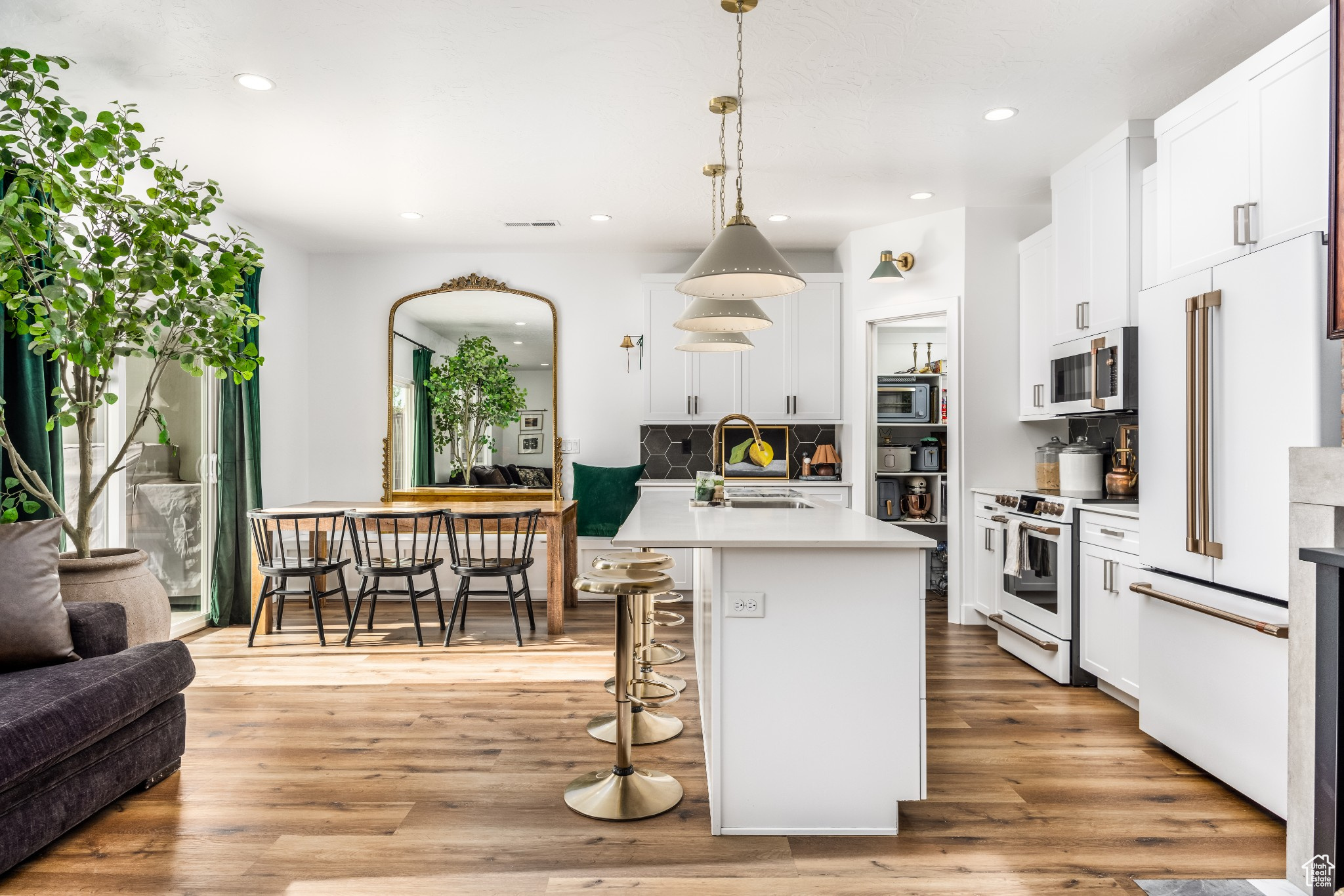 Modern Kitchen with white appliances, a center island with sink, Upgraded hanging light fixtures, and tasteful backsplash