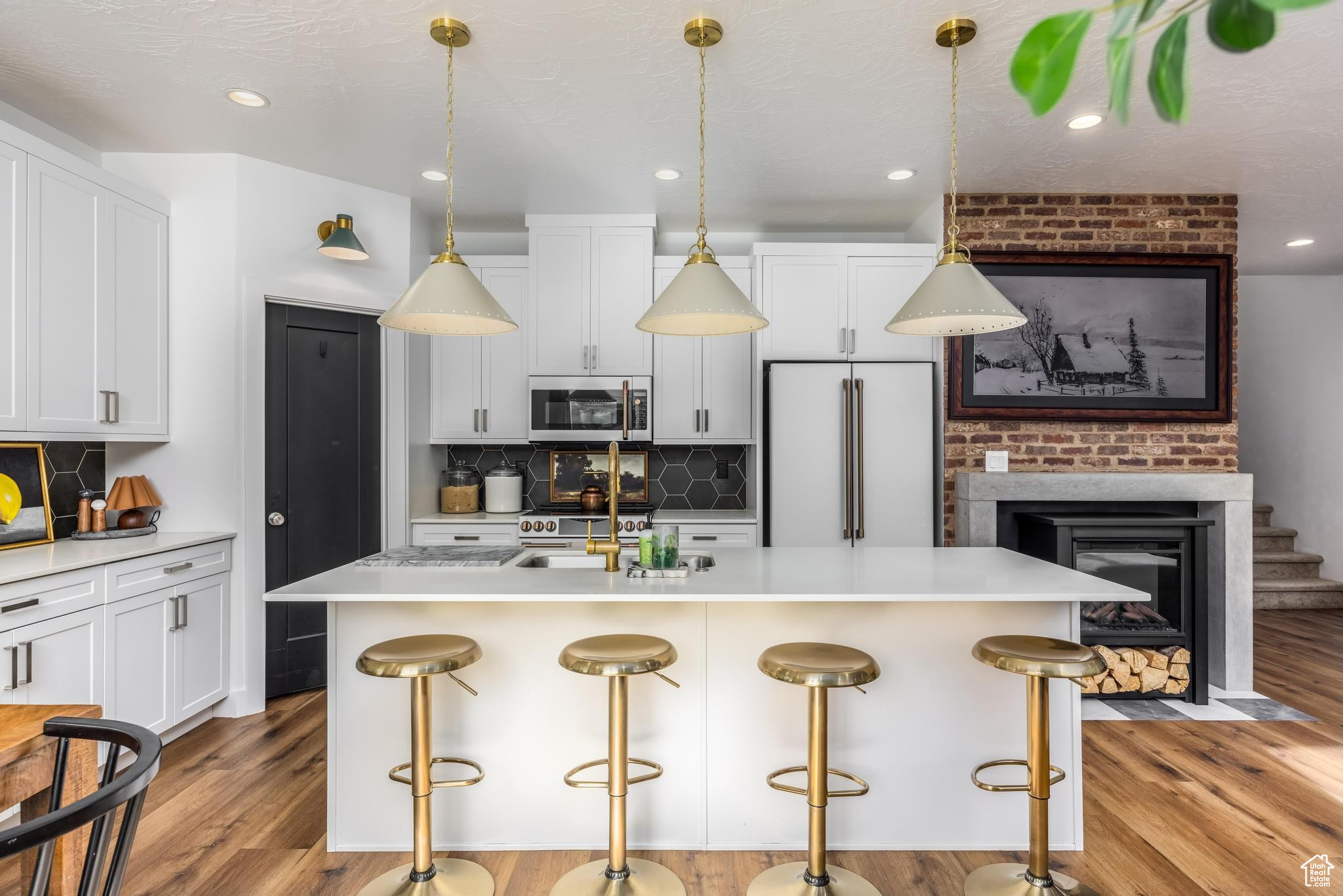 Kitchen featuring tasteful backsplash, white cabinetry, high end appliances, and an island with sink