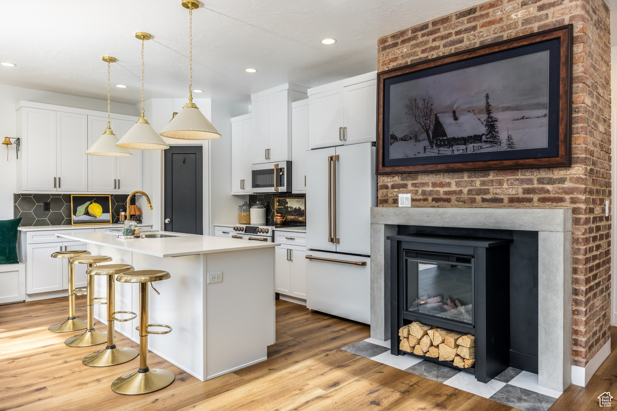 Kitchen with white cabinets, fireplace, wired for Picture TV, and a center island with sink