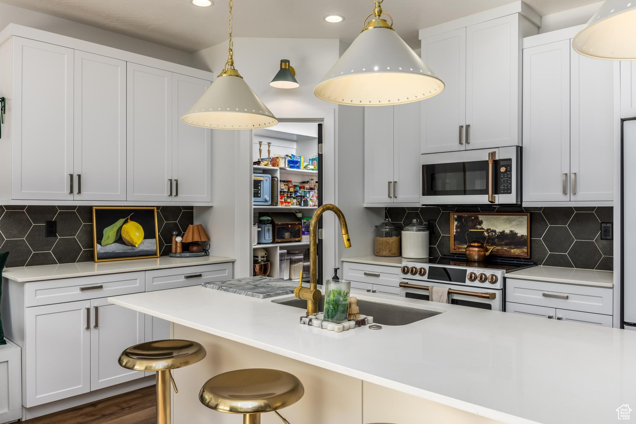 Kitchen featuring pendant lighting, white cabinets, a kitchen breakfast bar, sink, and tasteful backsplash