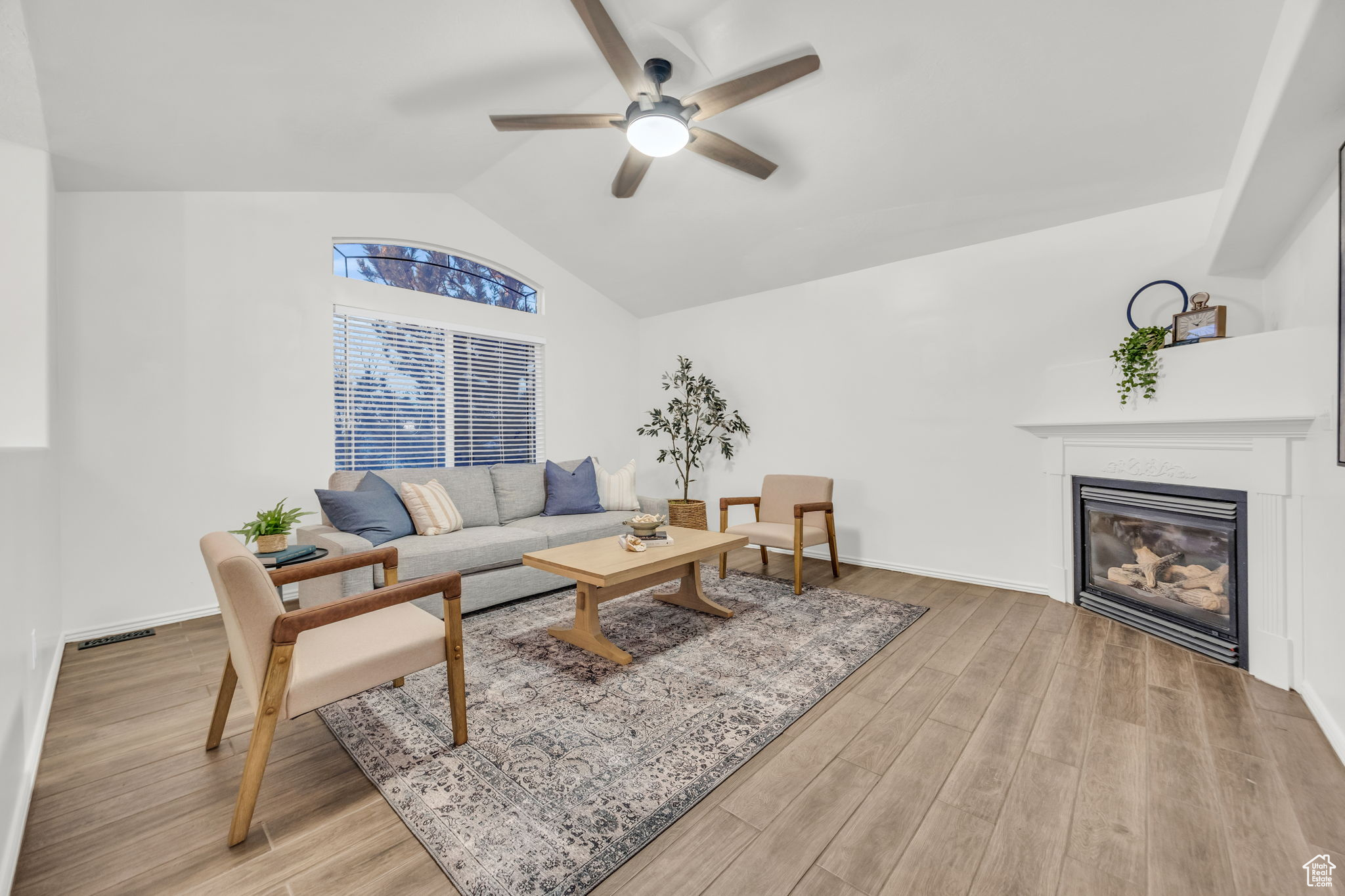 Living room with ceiling fan, tile wood-style flooring, and lofted ceiling