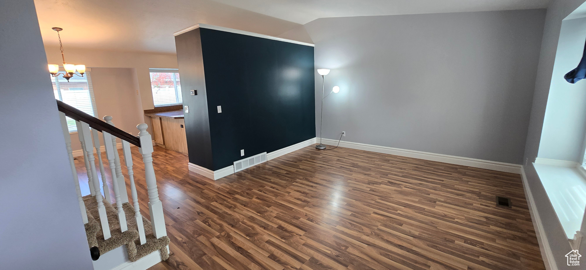 Living room featuring wood-style flooring, vaulted ceiling and green accent wall