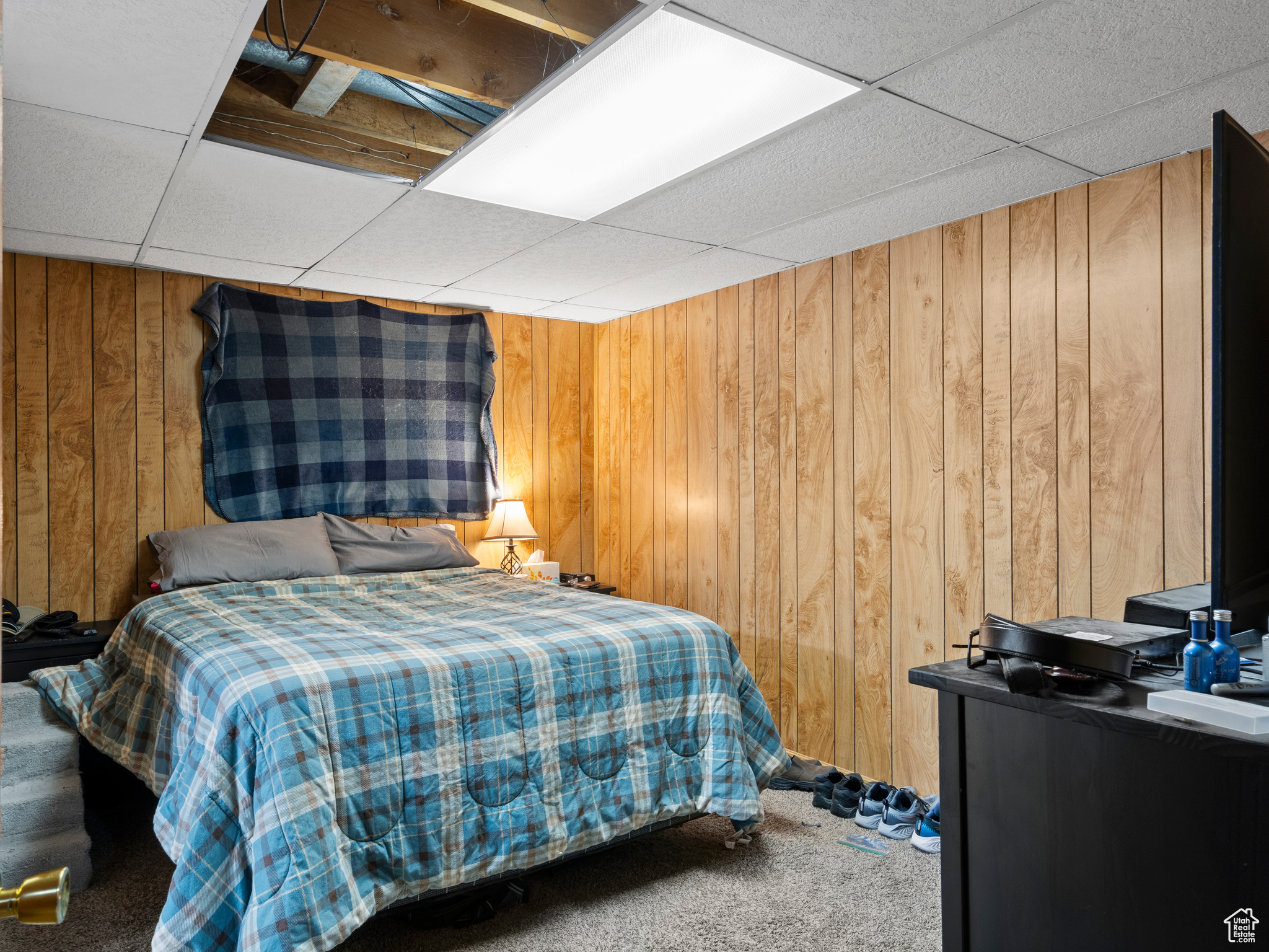 Carpeted bedroom with a paneled ceiling and wooden walls