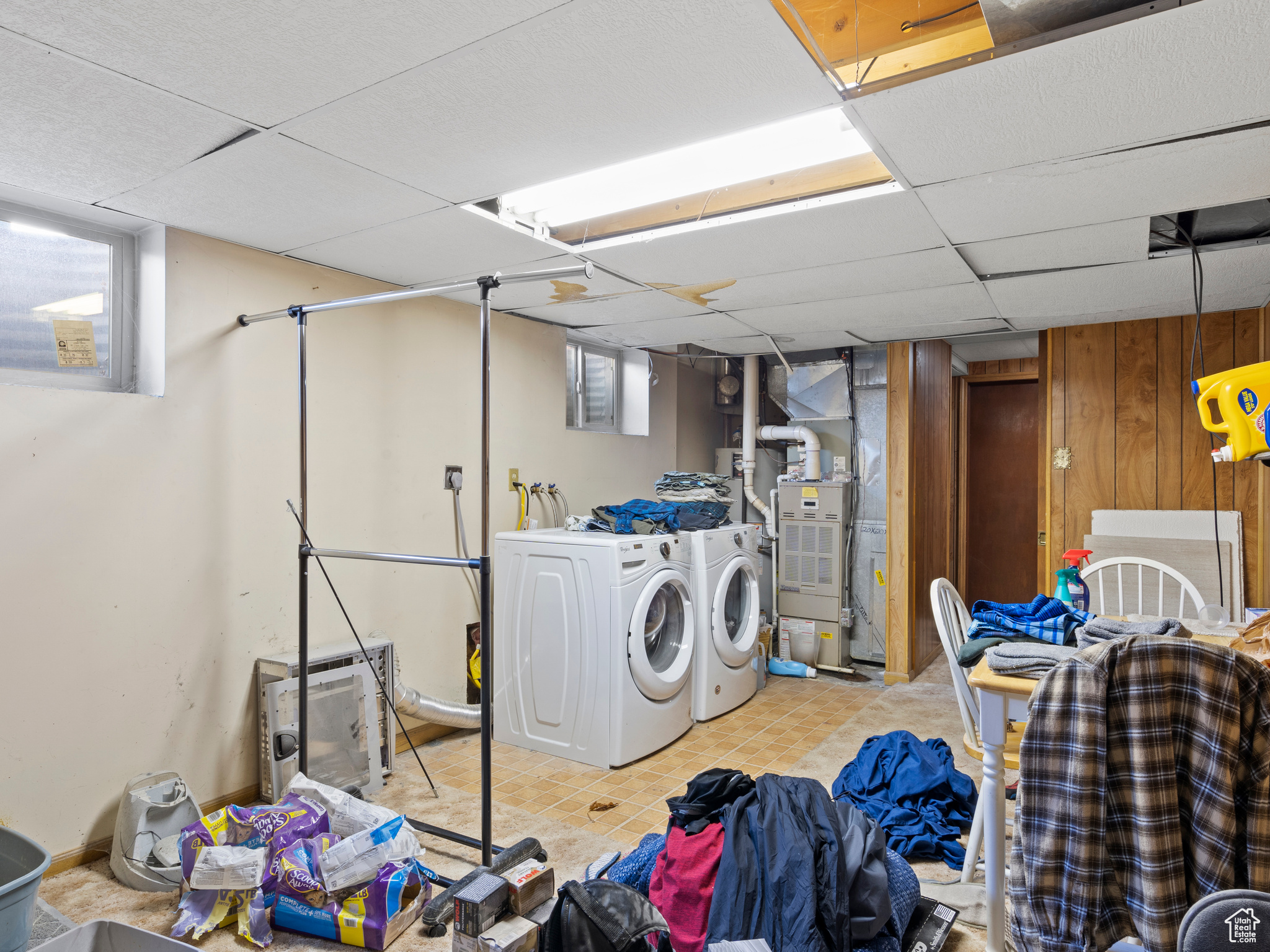 Laundry area with heating unit, light tile patterned flooring, wooden walls, and washing machine and clothes dryer