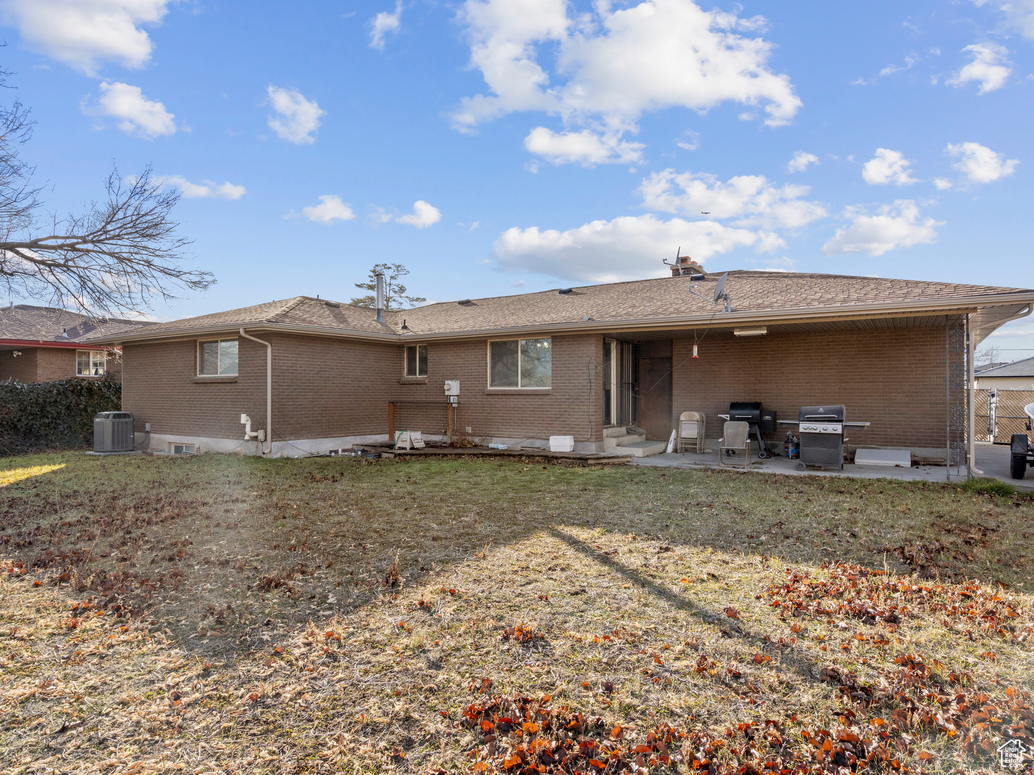 Rear view of house with a lawn, central air condition unit, and a patio