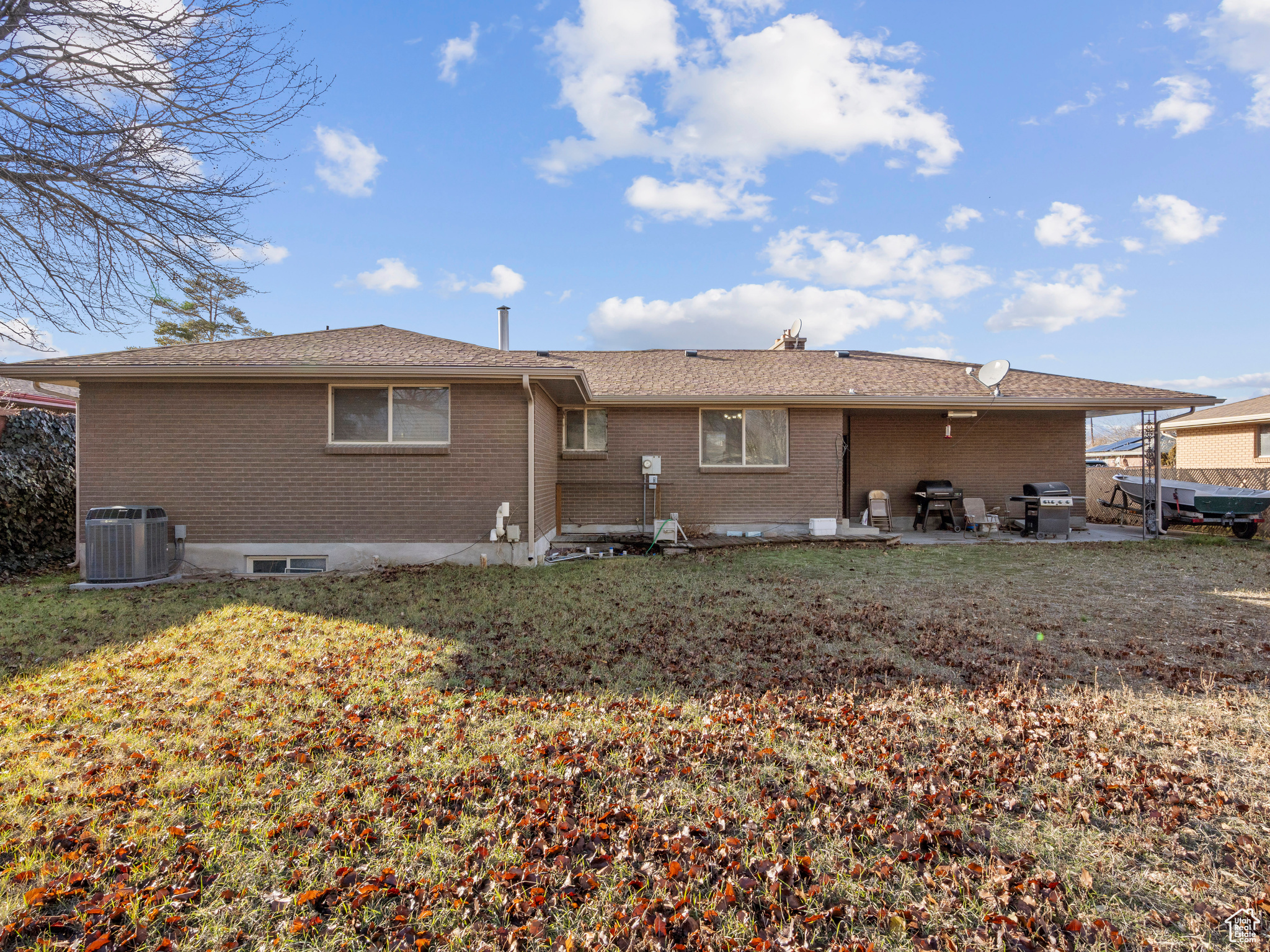 Back of property with a lawn, a patio area, and central AC