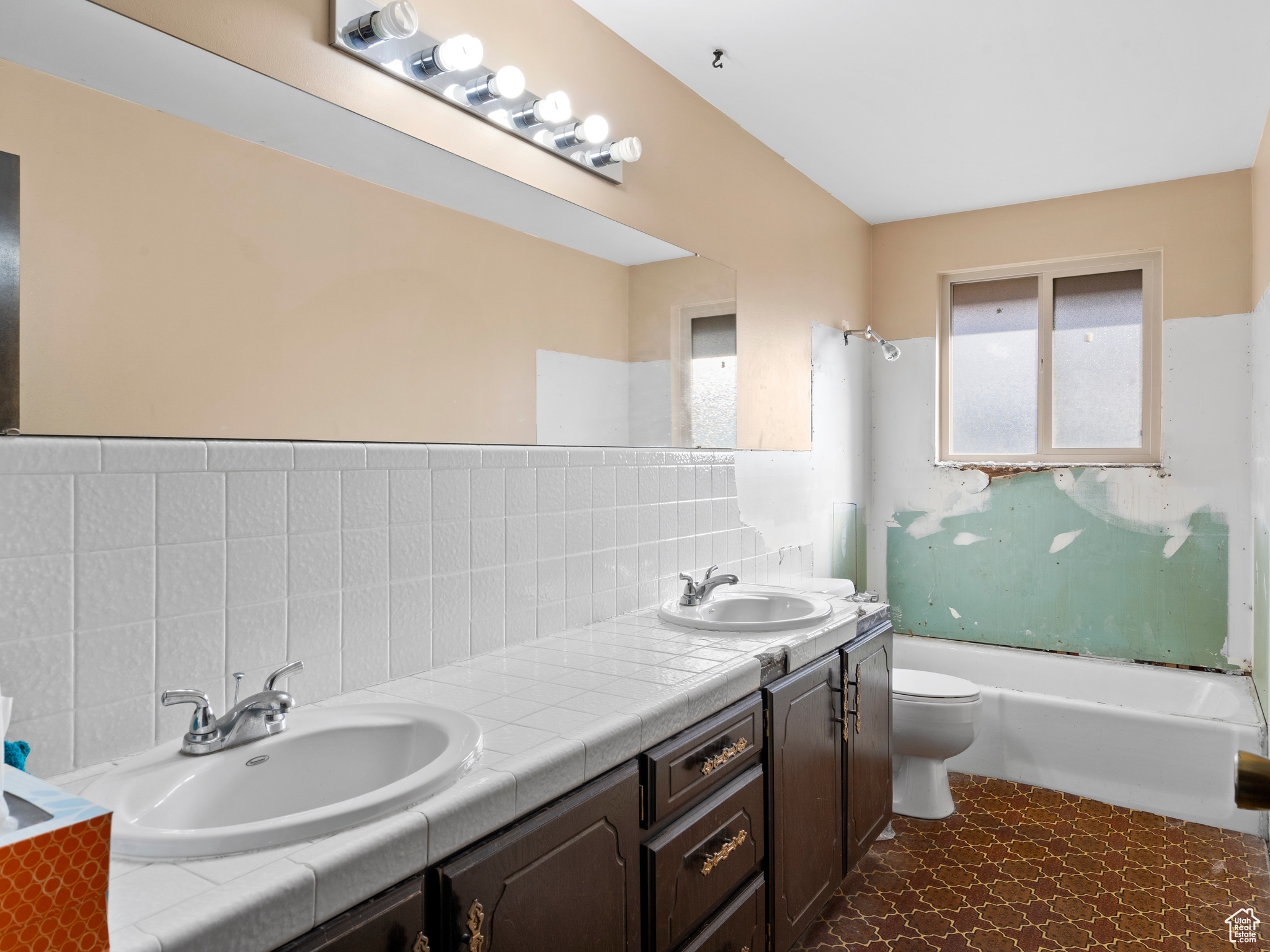 Full bathroom featuring washtub / shower combination, vanity, toilet, and backsplash