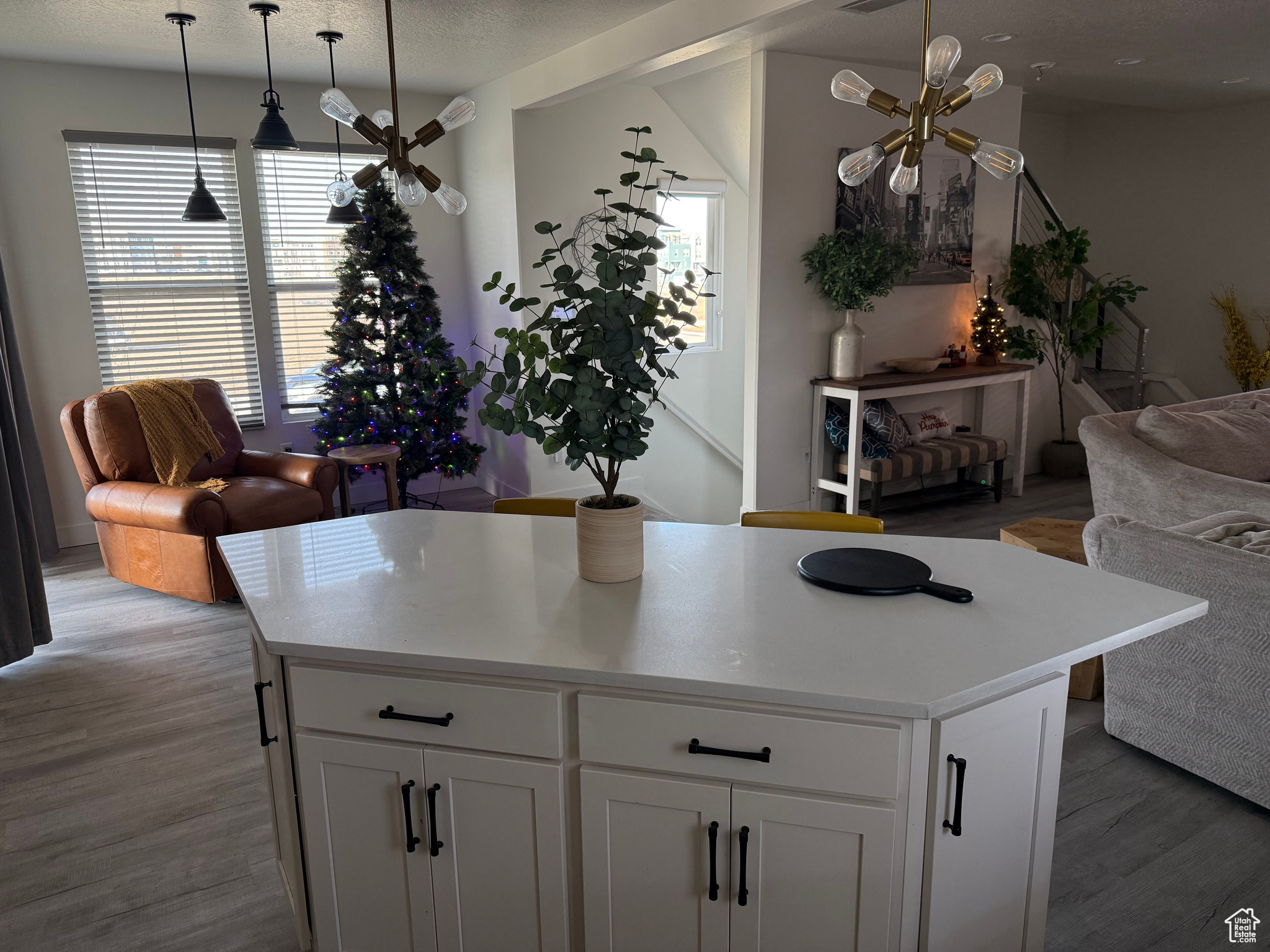 Kitchen with white cabinetry, a kitchen island, light hardwood / wood-style floors, and decorative light fixtures