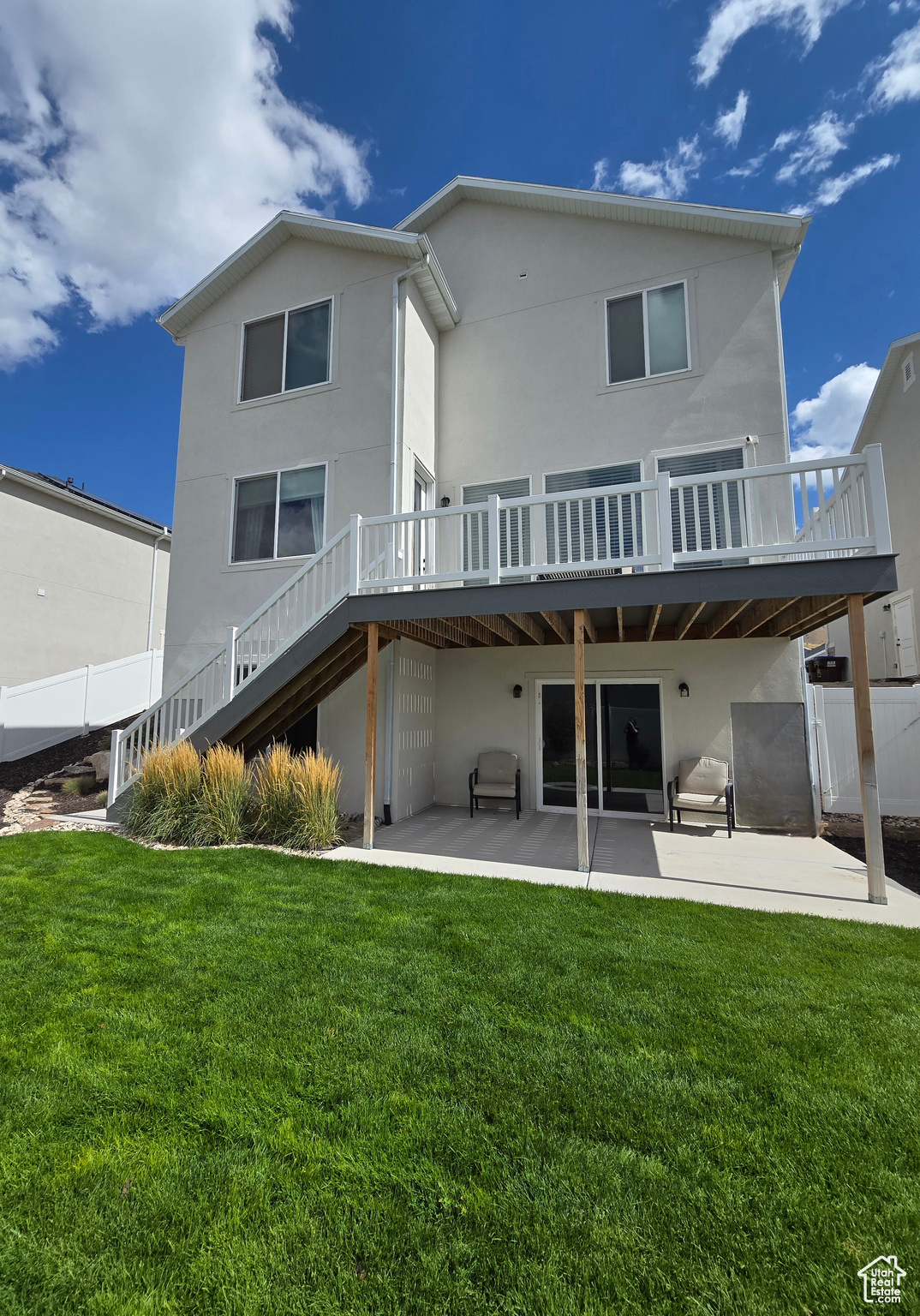 Rear view of property featuring a wooden deck, a patio area, and a yard