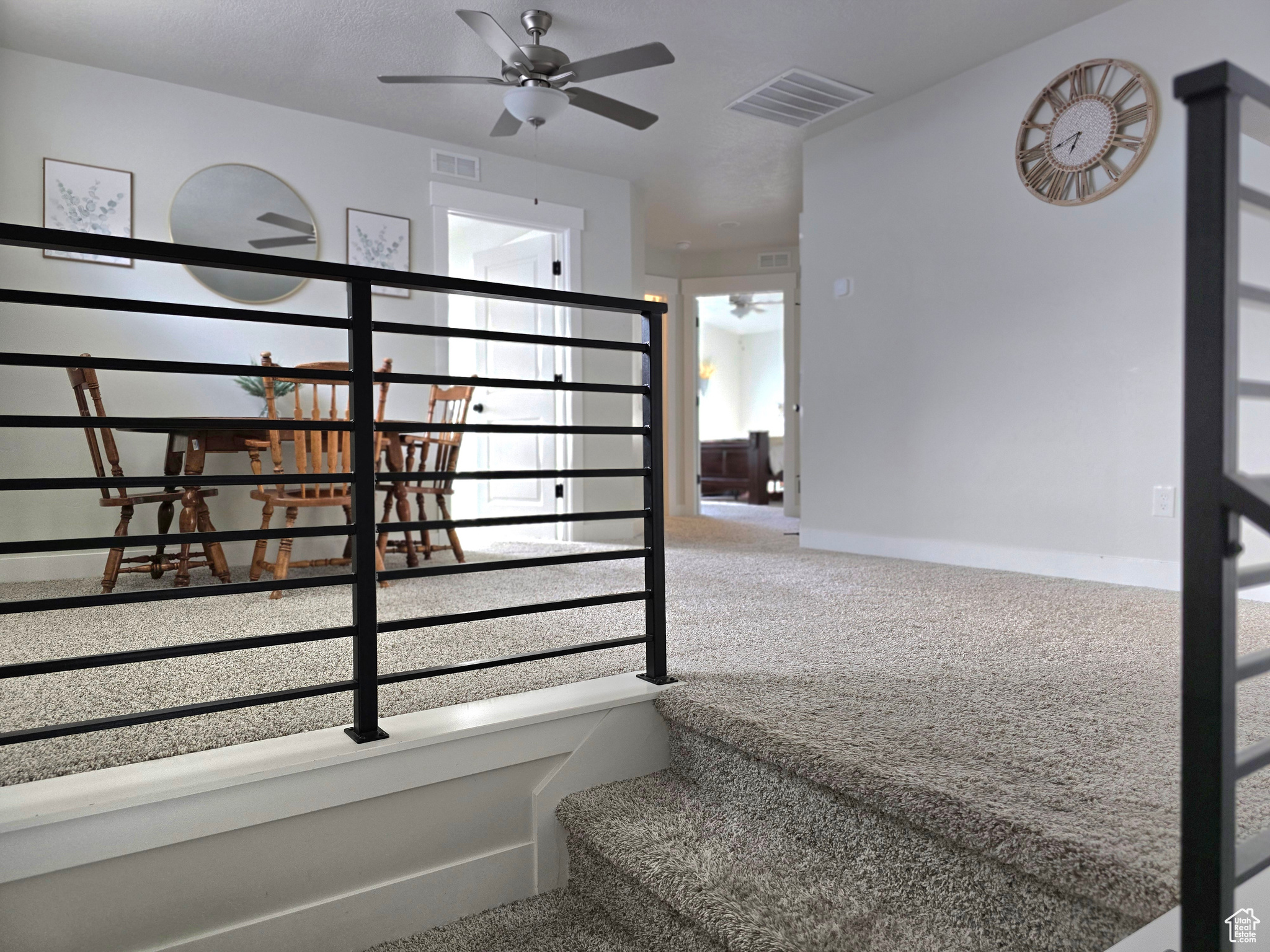 Stairs featuring carpet floors, ceiling fan, and a healthy amount of sunlight