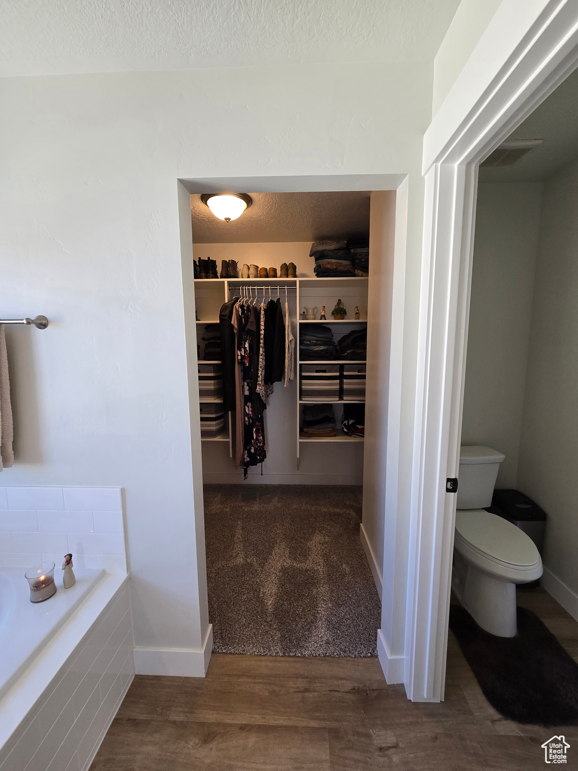 Bathroom with a washtub, wood-type flooring, a textured ceiling, and toilet