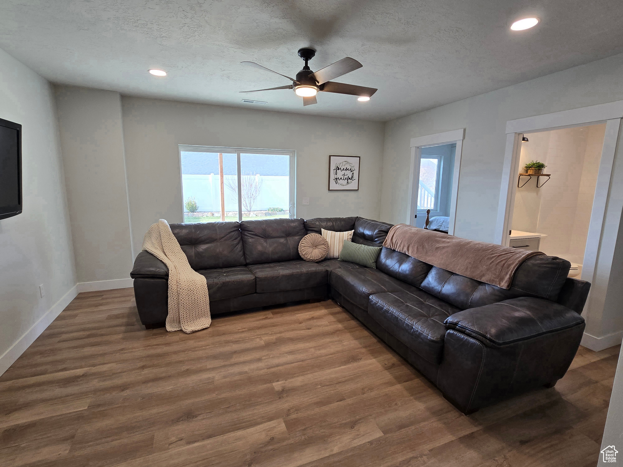 Living room featuring ceiling fan, wood-type flooring, and a textured ceiling