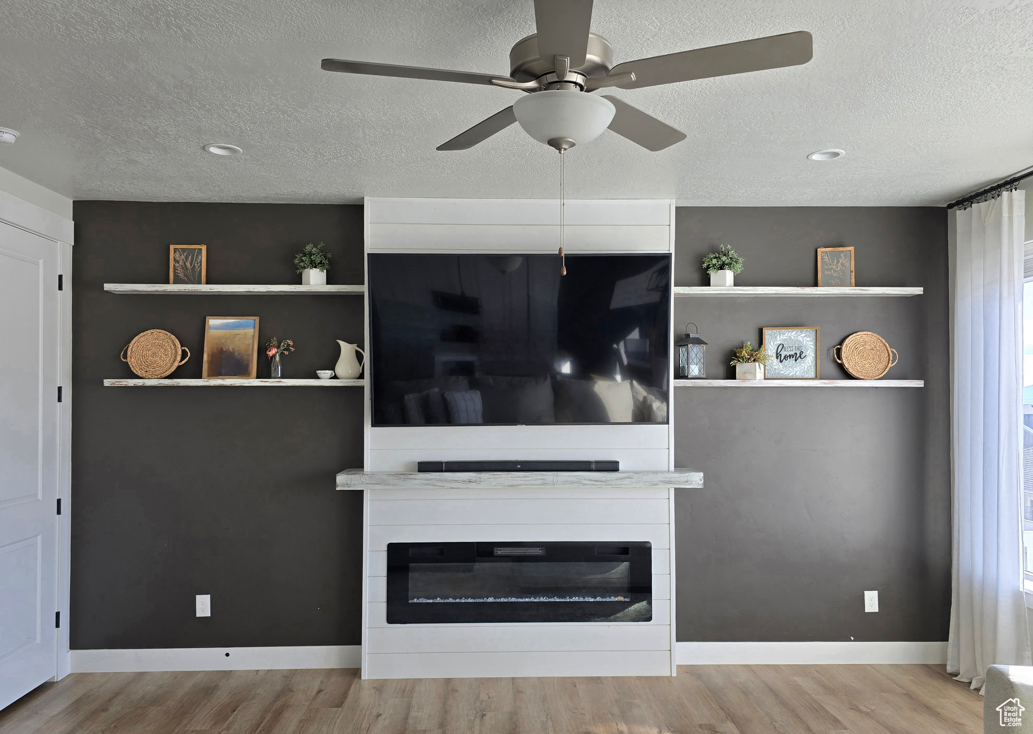 Unfurnished living room featuring a large fireplace, a textured ceiling, and light hardwood / wood-style flooring