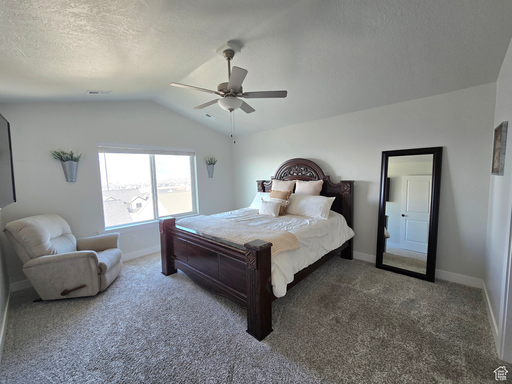 Carpeted bedroom with a textured ceiling, ceiling fan, and lofted ceiling