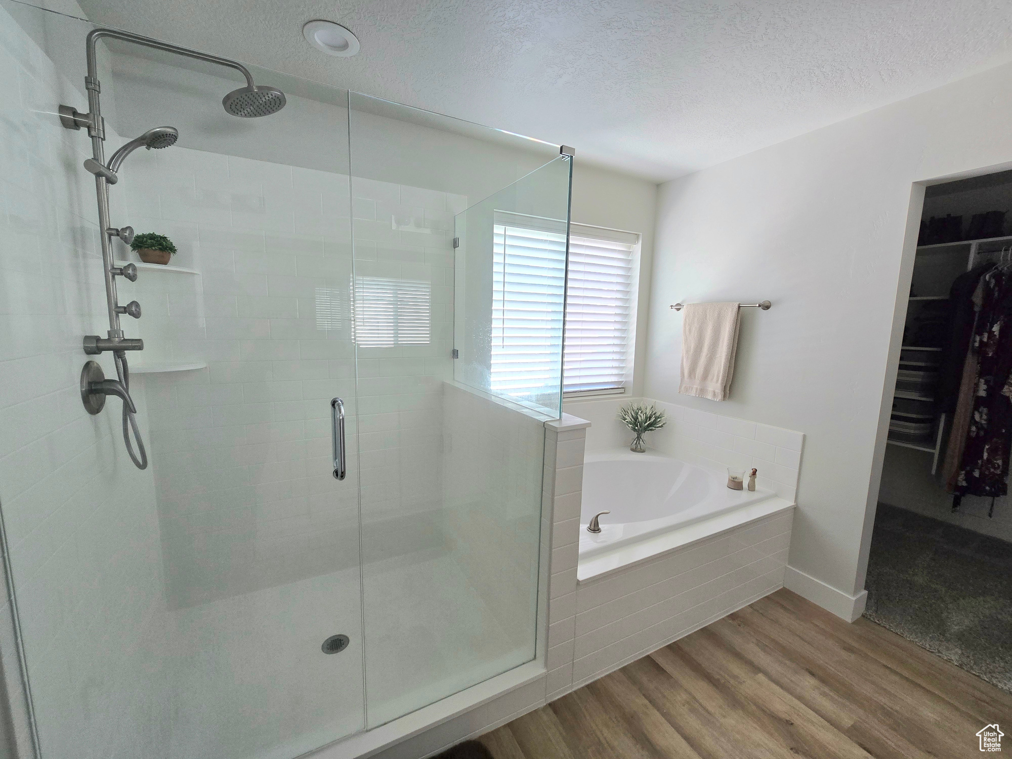 Bathroom featuring plus walk in shower, wood-type flooring, and a textured ceiling