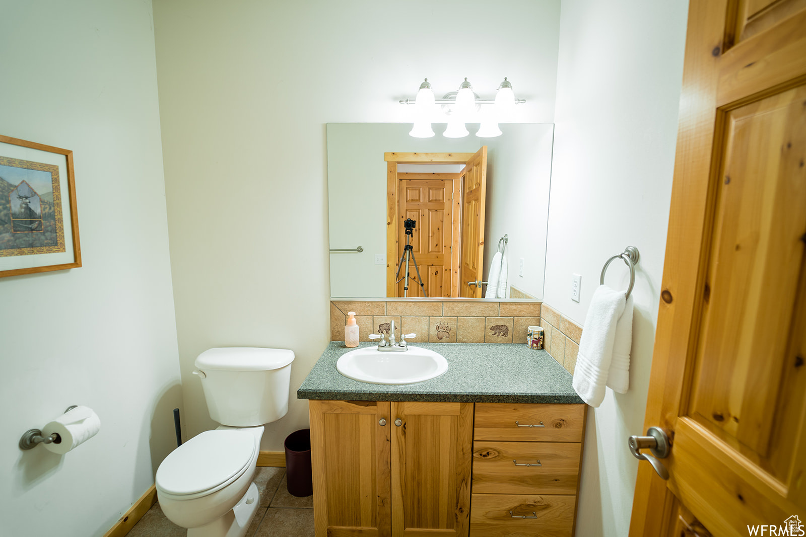 Bathroom featuring decorative backsplash, vanity, tile patterned floors, and toilet