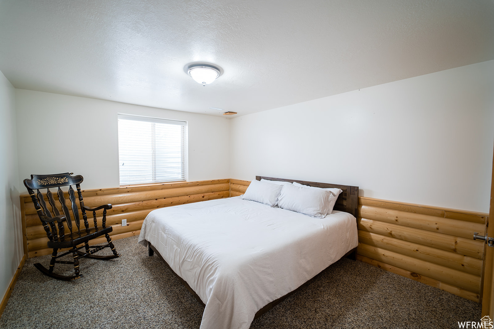 Carpeted bedroom with log walls