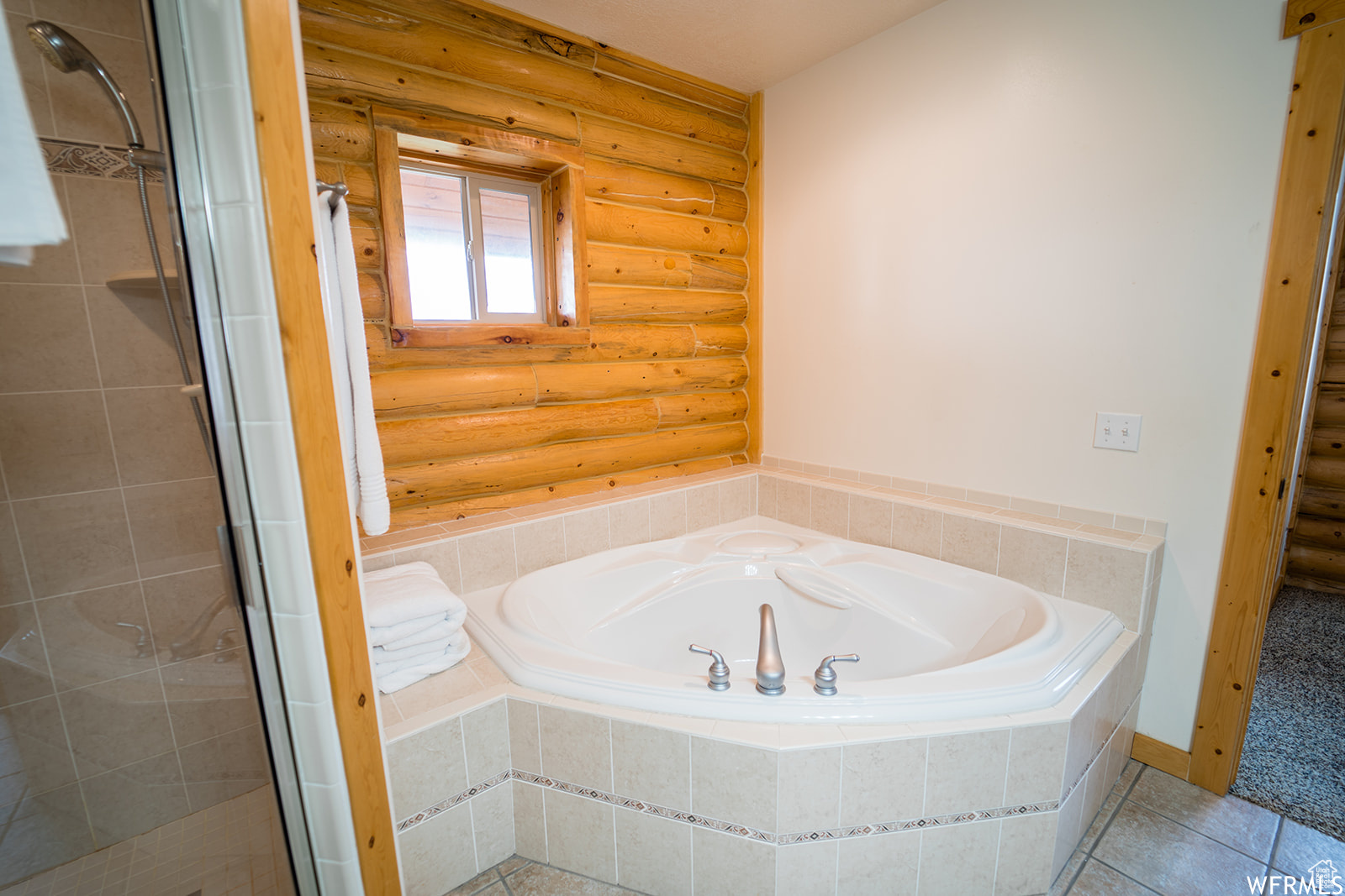 Bathroom featuring rustic walls, tile patterned flooring, and independent shower and bath