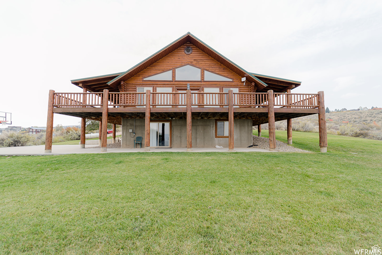 Back of property featuring a deck, a patio area, and a lawn