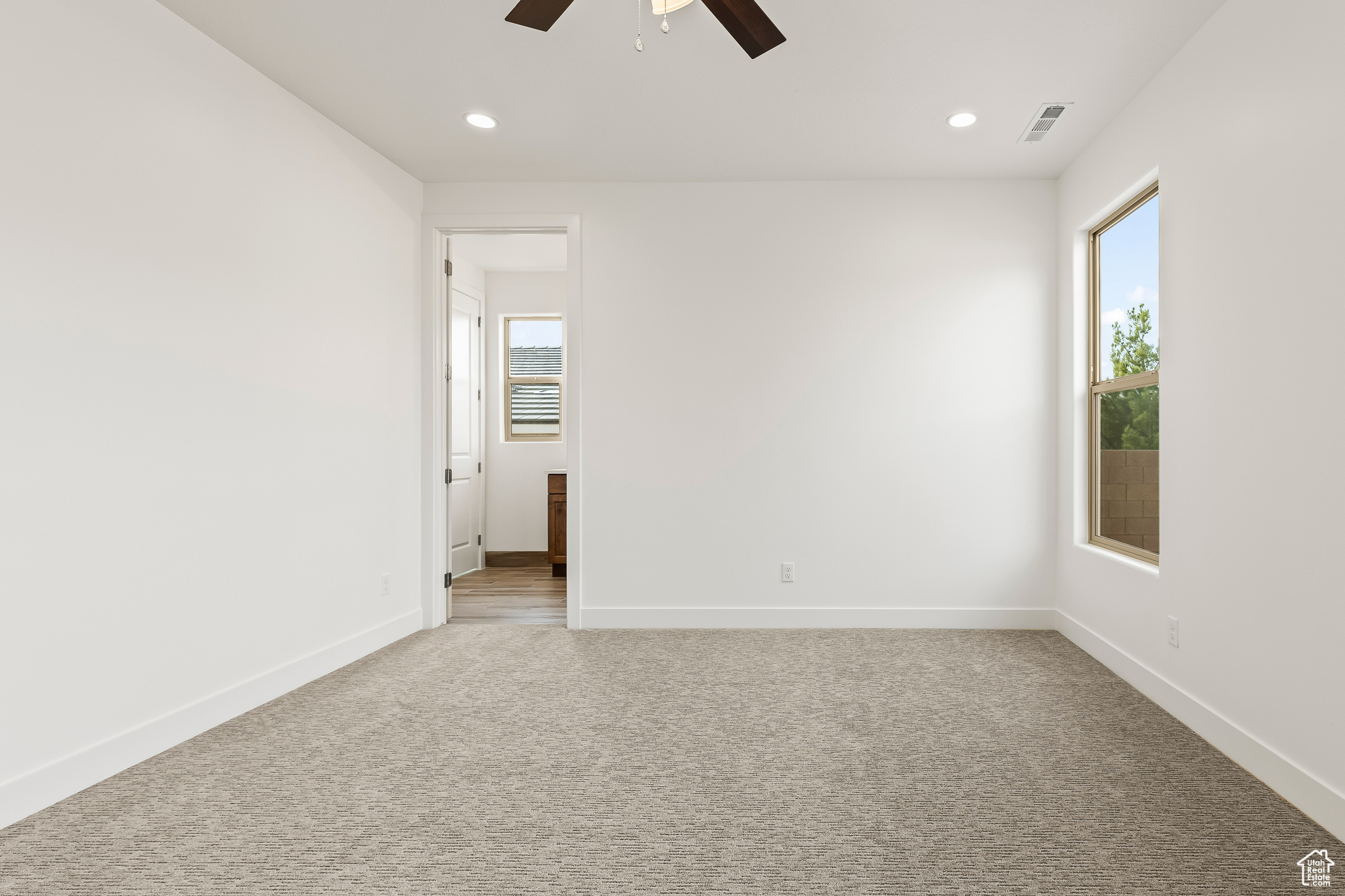 Empty room with ceiling fan and light colored carpet