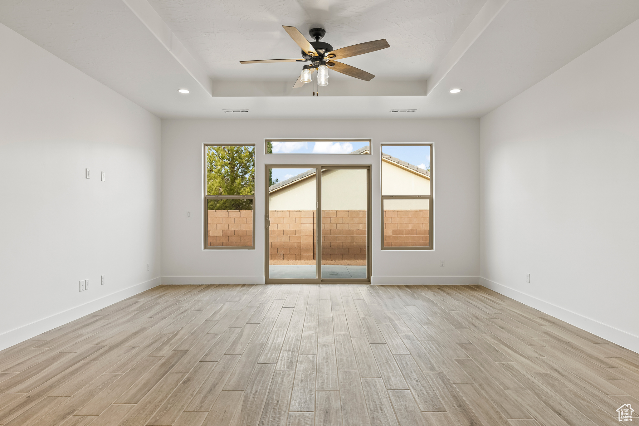 Unfurnished room with ceiling fan, a healthy amount of sunlight, and a raised ceiling