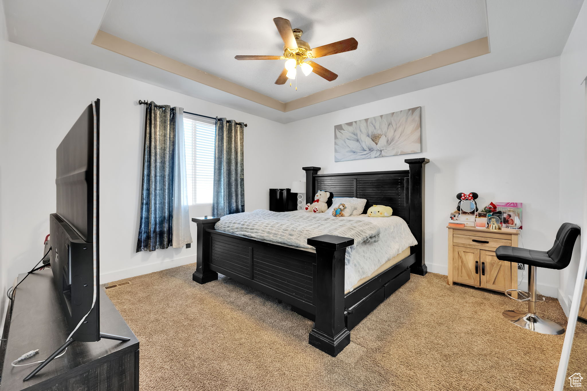 Bedroom featuring a tray ceiling, ceiling fan, and light carpet