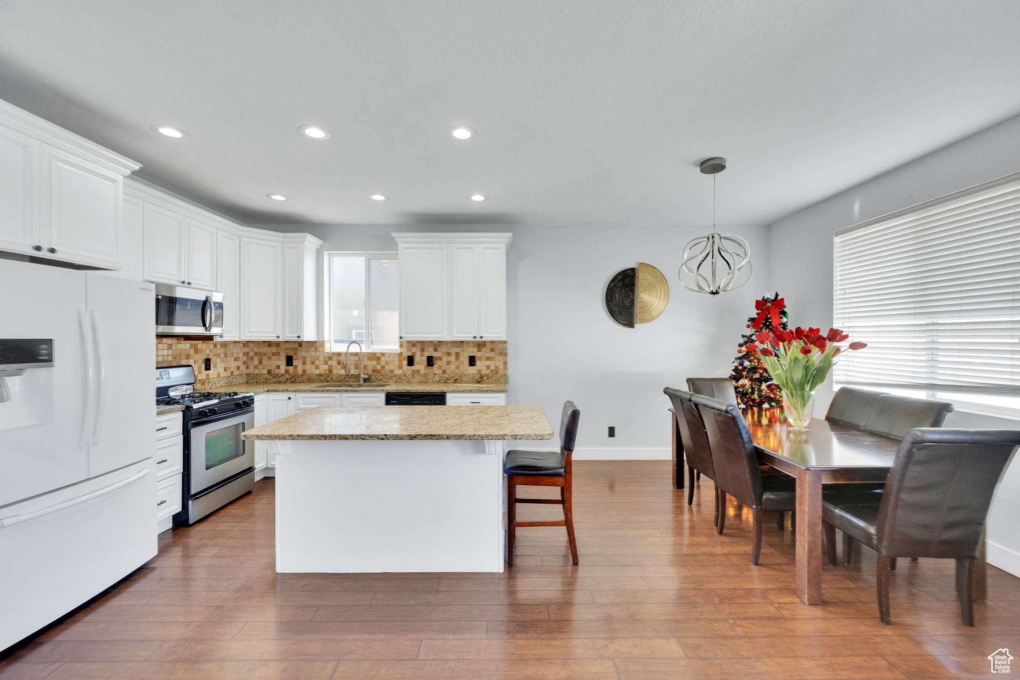 Kitchen featuring white cabinets, hanging light fixtures, and appliances with stainless steel finishes