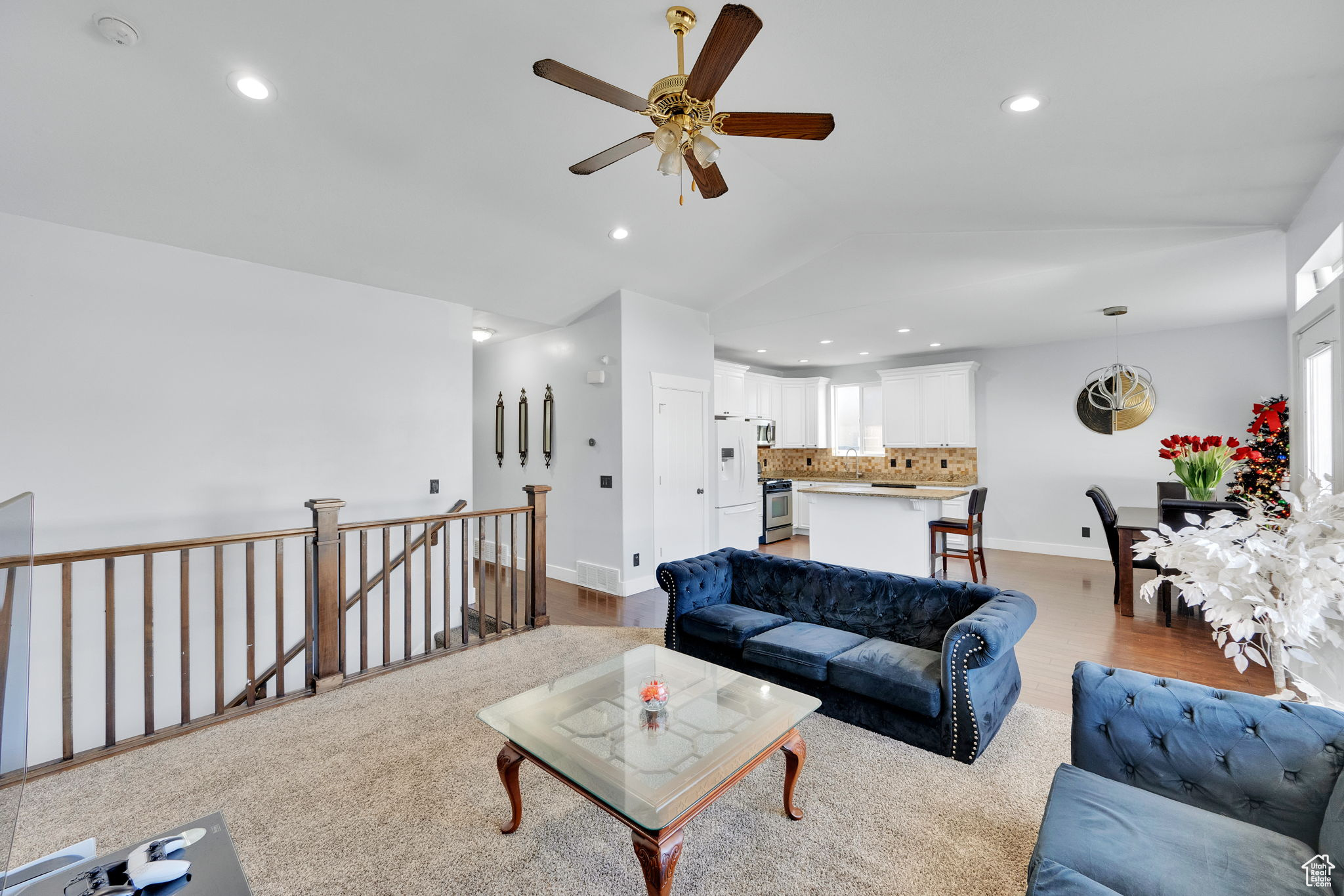 Living room with light hardwood / wood-style floors, ceiling fan, and lofted ceiling