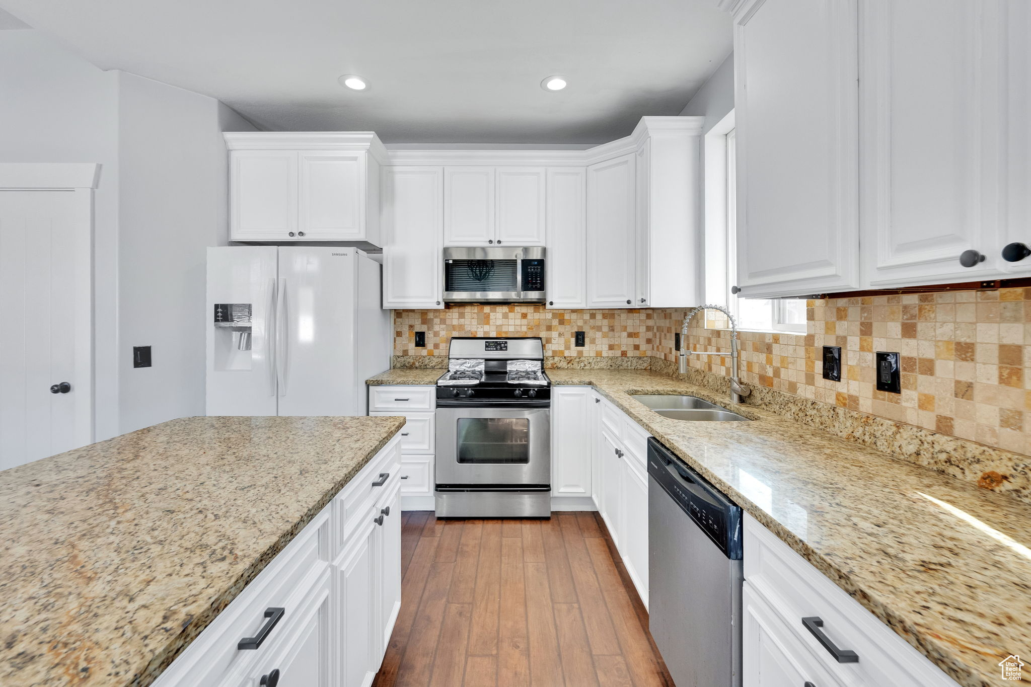 Kitchen with white cabinets, backsplash, sink, and stainless steel appliances