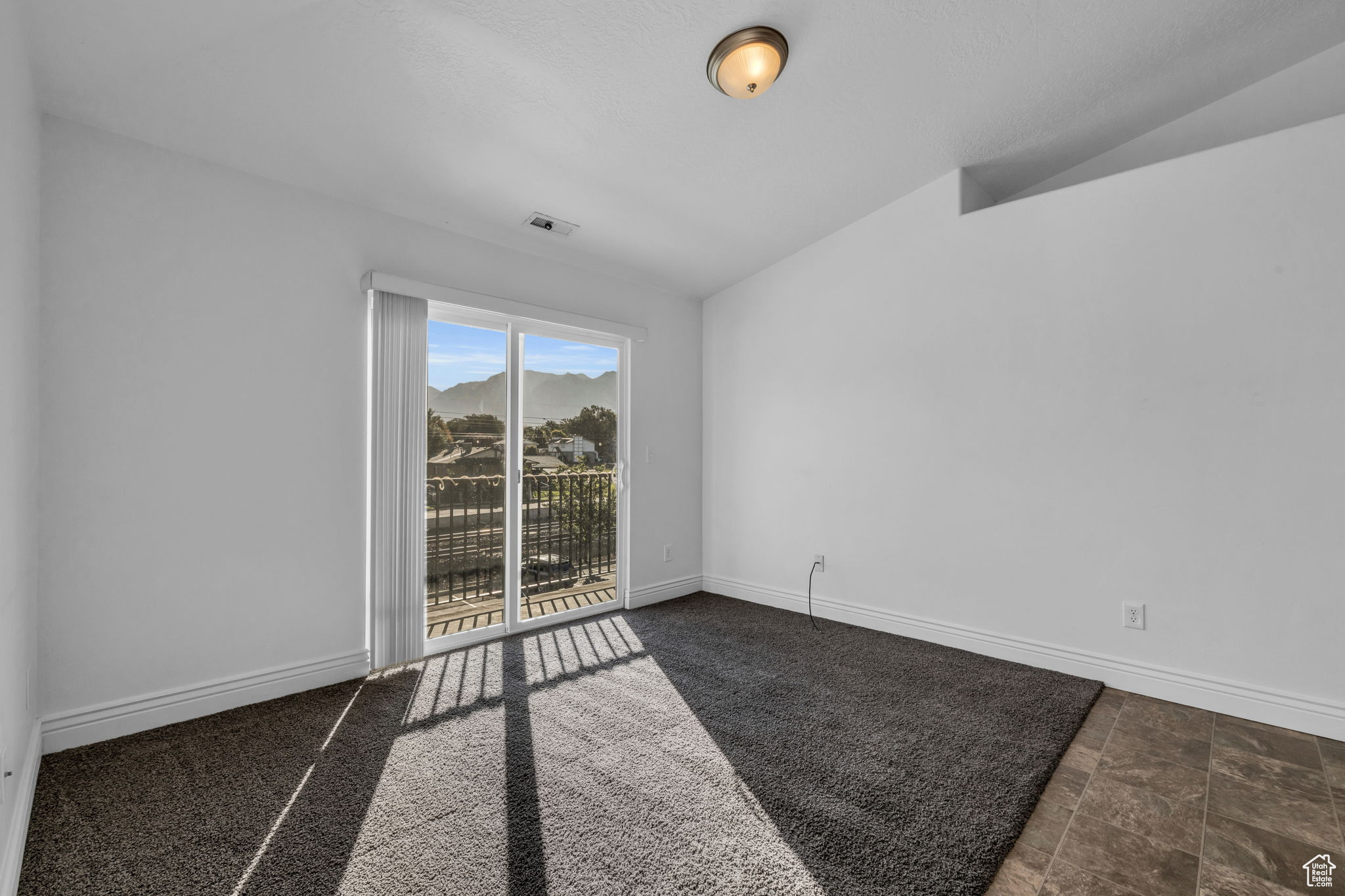 Living room with vaulted ceiling and access to the balcony with storage