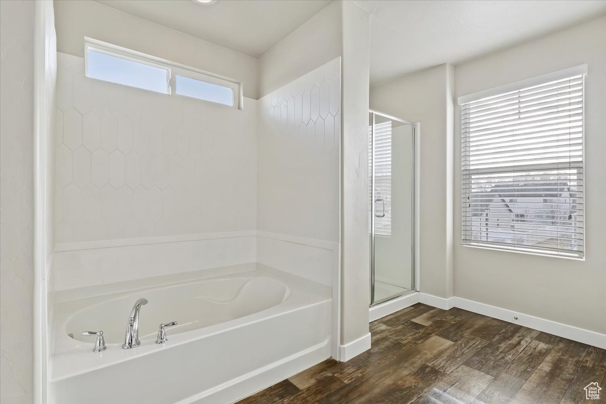 Bathroom featuring shower with separate batSpacious Ensuite Bathroom with a double vanity, a soaking tub and an enclosed showerhtub, a wealth of natural light, and wood-type flooring