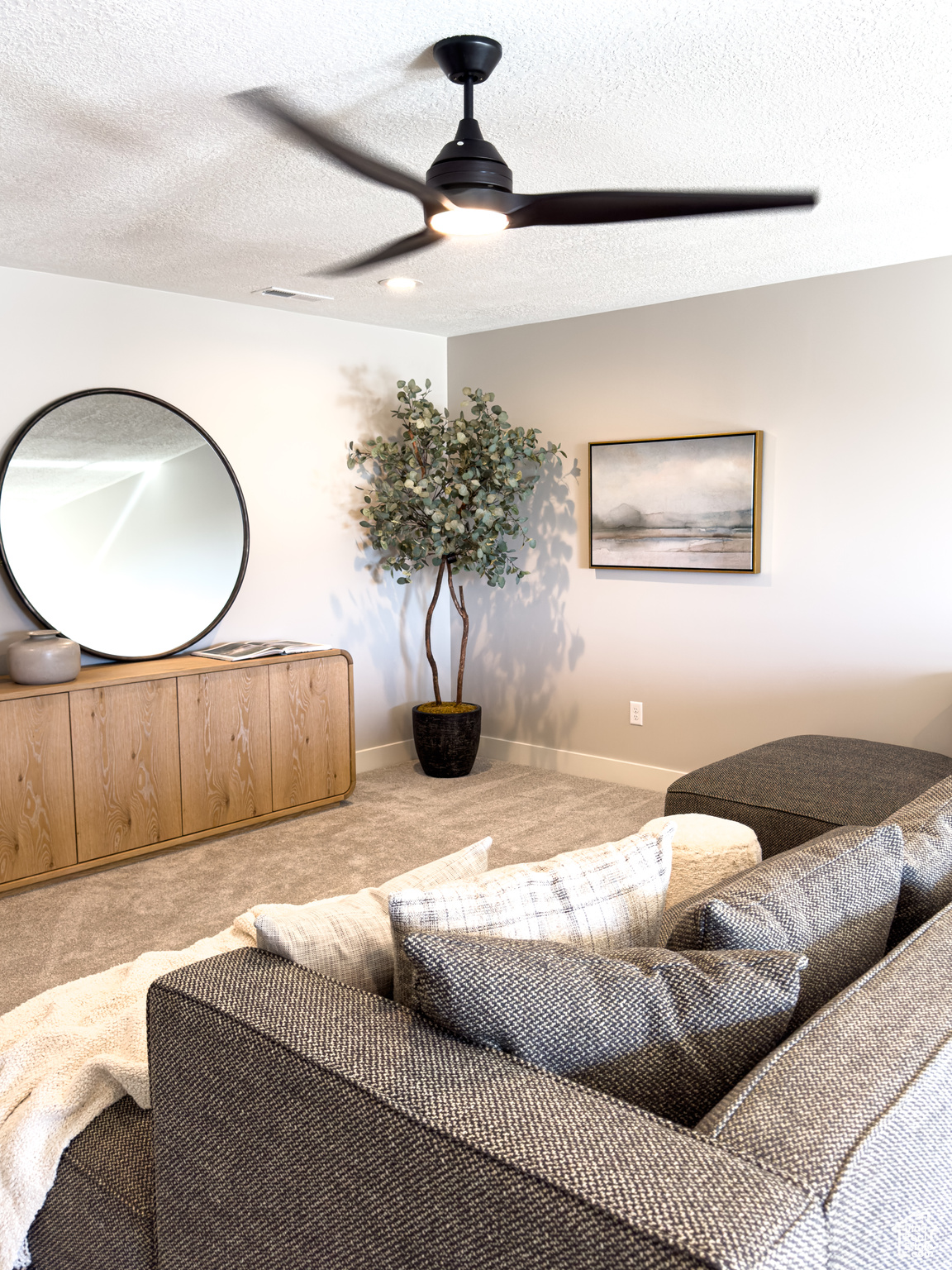 Carpeted living room featuring ceiling fan and a textured ceiling