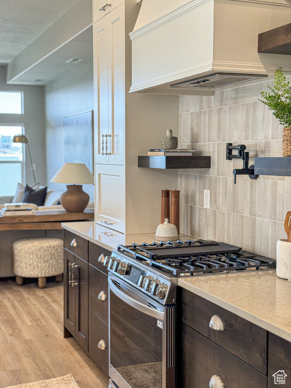 Kitchen featuring gas stove, dark brown cabinetry, tasteful backsplash, light hardwood / wood-style flooring, and premium range hood