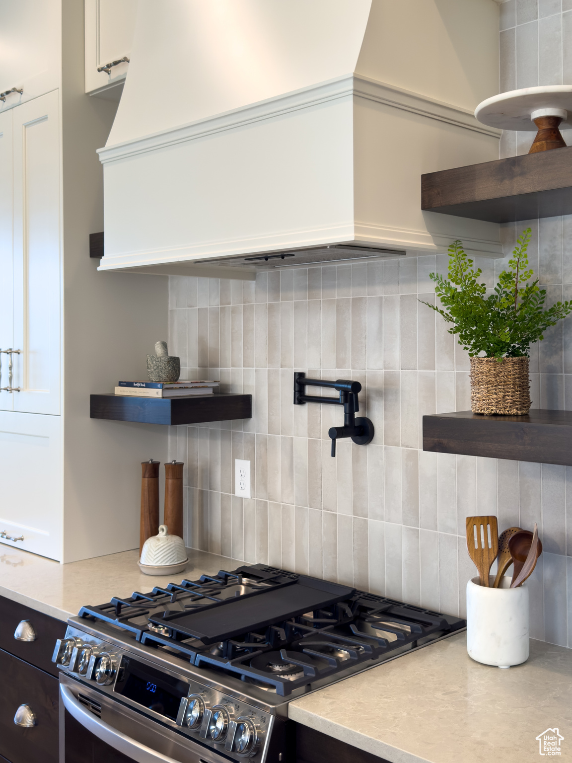 Kitchen with white cabinetry, high end stove, and backsplash