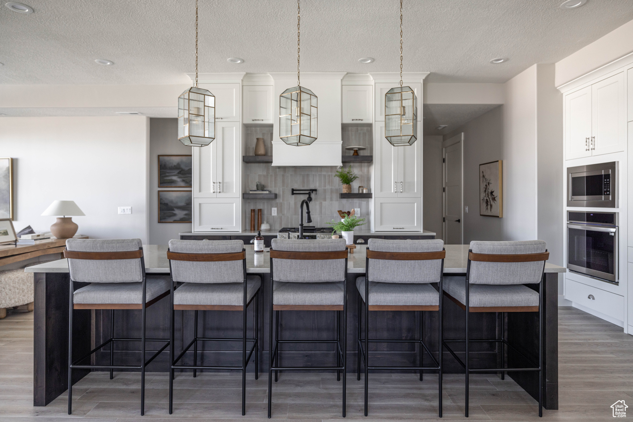 Kitchen with white cabinets, appliances with stainless steel finishes, pendant lighting, and a large island