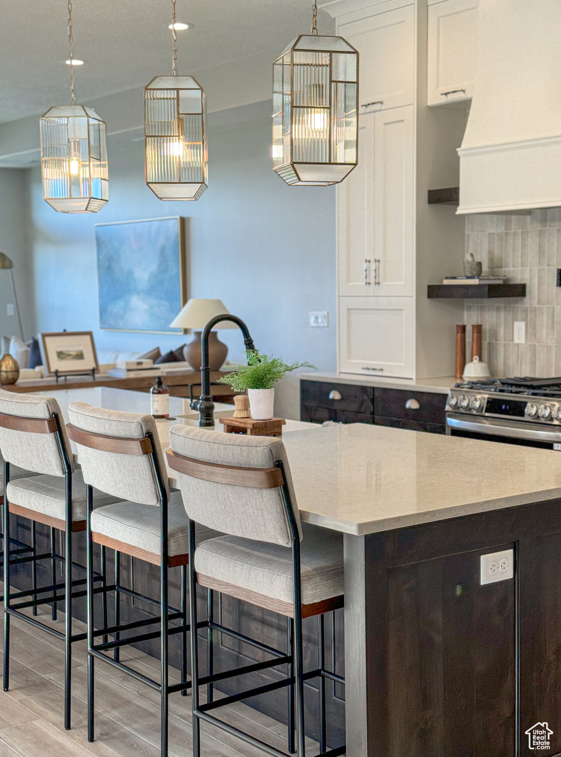 Kitchen featuring exhaust hood, decorative backsplash, light wood-type flooring, a kitchen island, and white cabinetry