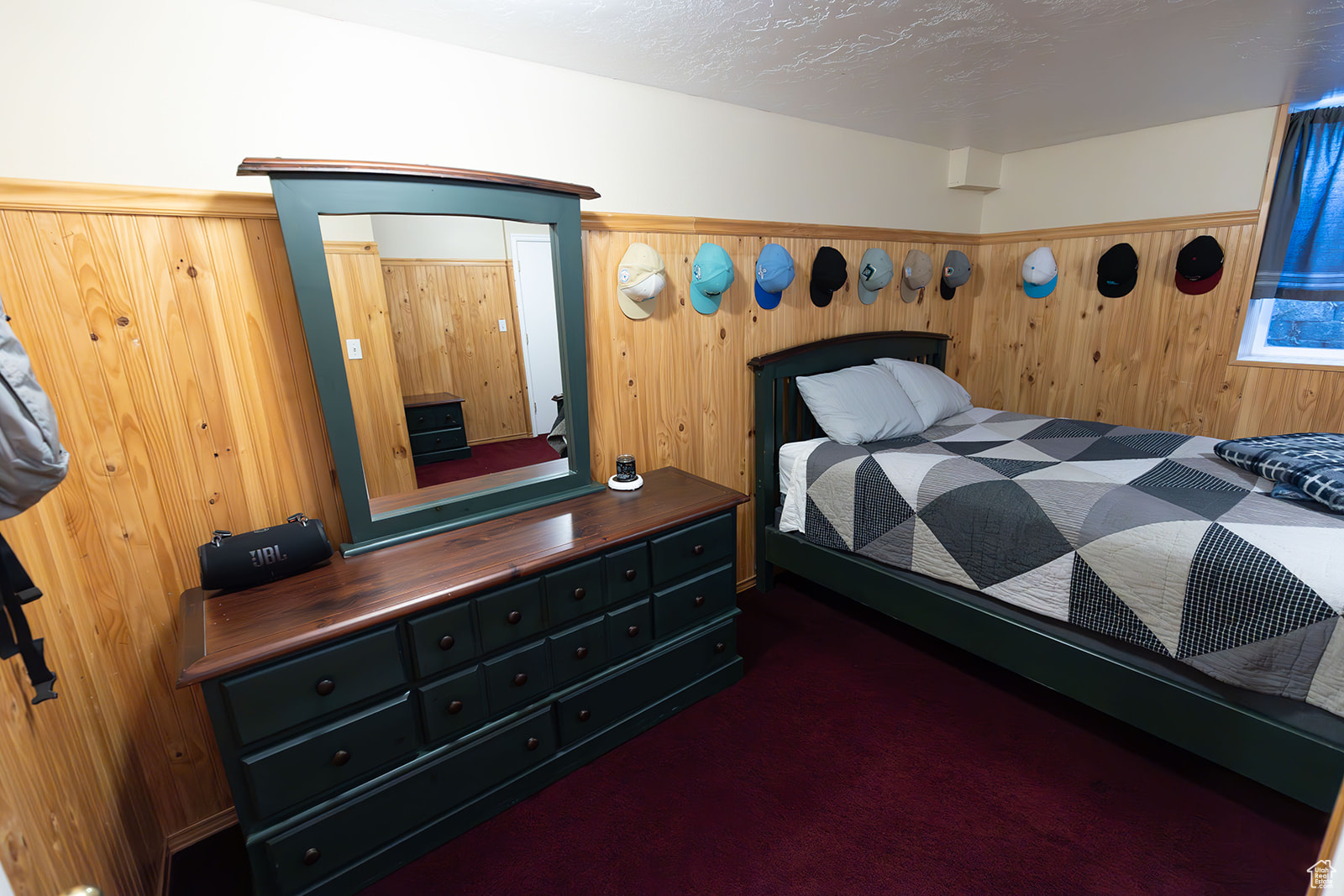 Carpeted bedroom featuring a textured ceiling and wooden walls