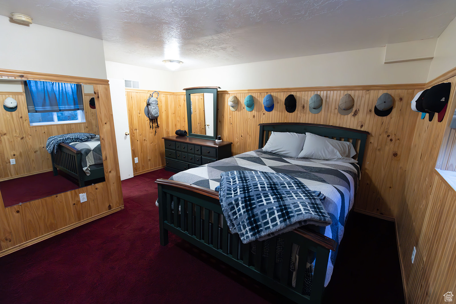 Bedroom featuring a textured ceiling, dark carpet, and wood walls