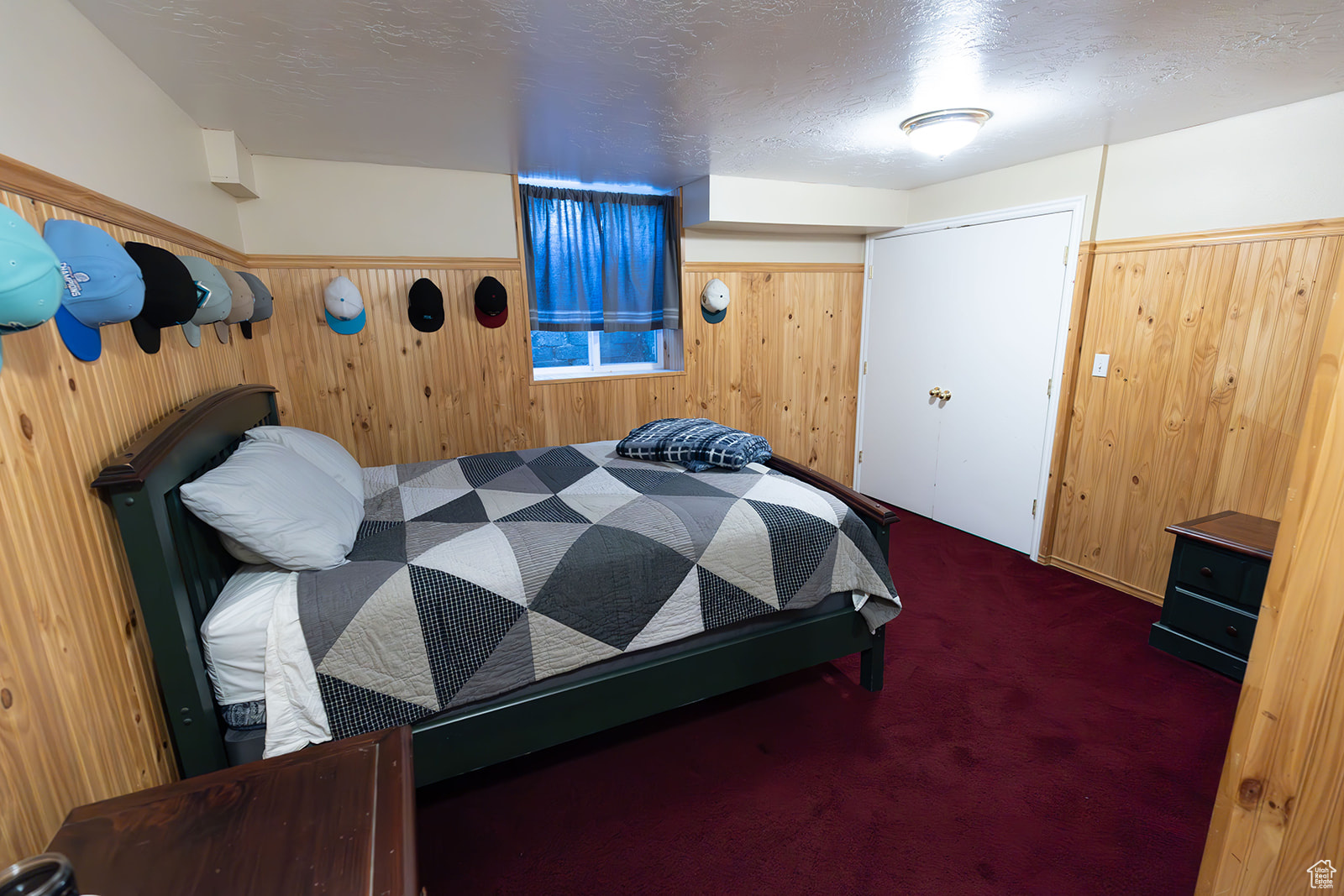 Bedroom featuring dark colored carpet, a textured ceiling, and wooden walls