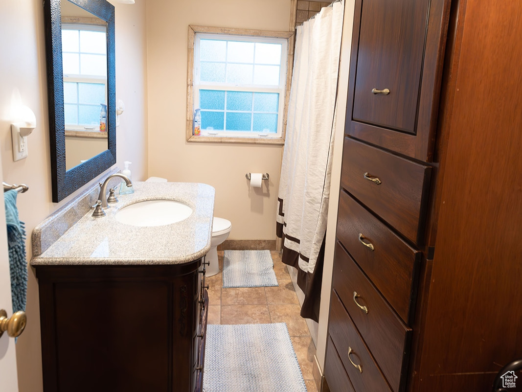 Bathroom with tile patterned flooring, vanity, toilet, and a healthy amount of sunlight