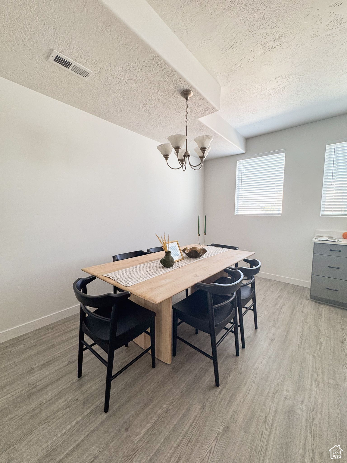 Dining area featuring a healthy amount of sunlight, light hardwood / wood-style floors, and an inviting chandelier