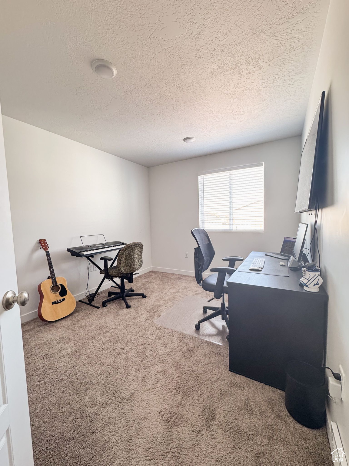 Carpeted office space featuring a textured ceiling