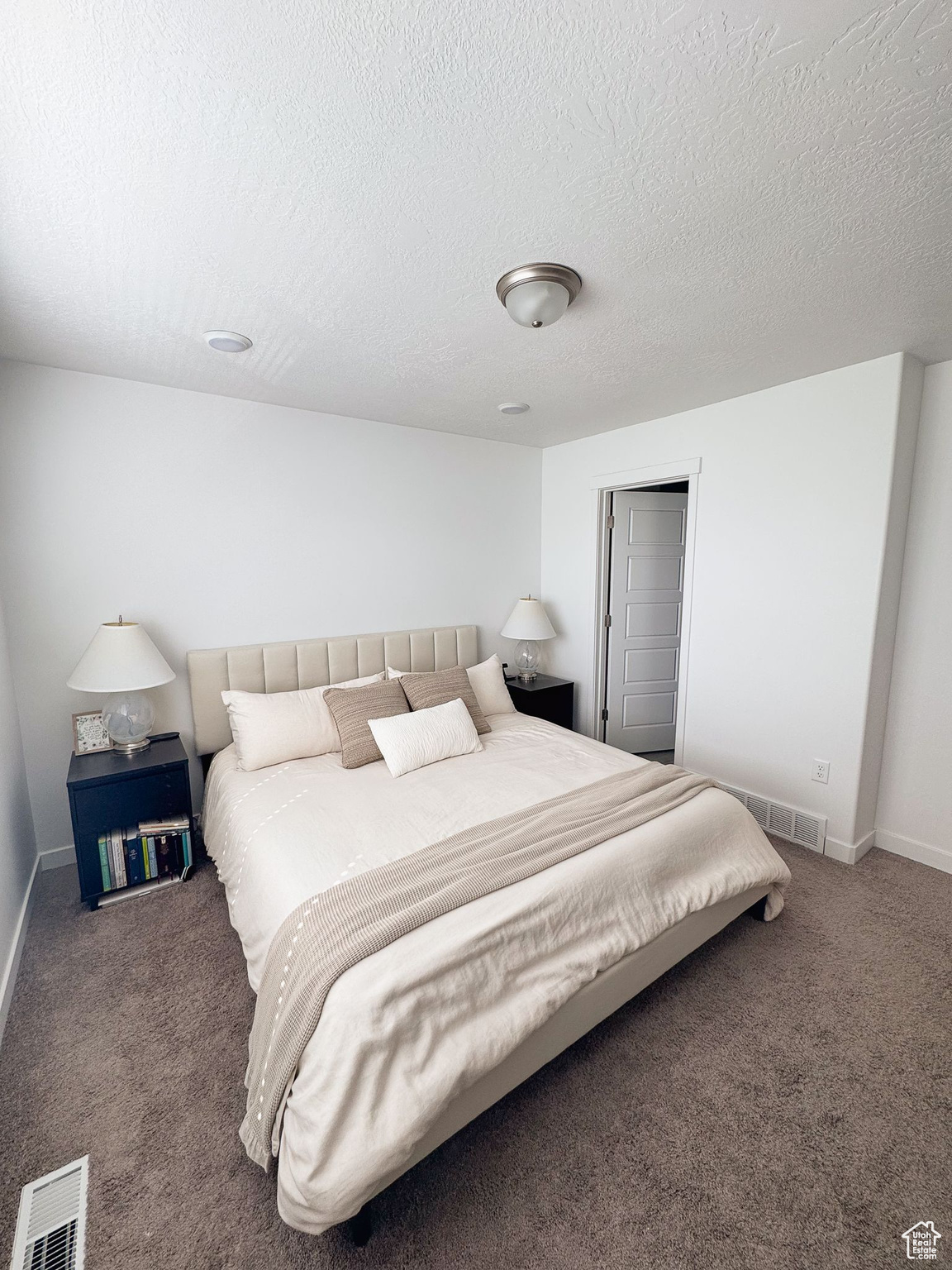 Carpeted bedroom featuring a textured ceiling and a closet