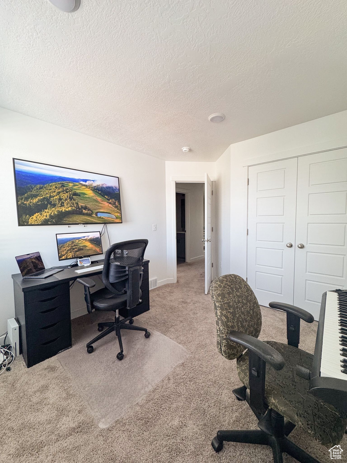 Carpeted office space with a textured ceiling