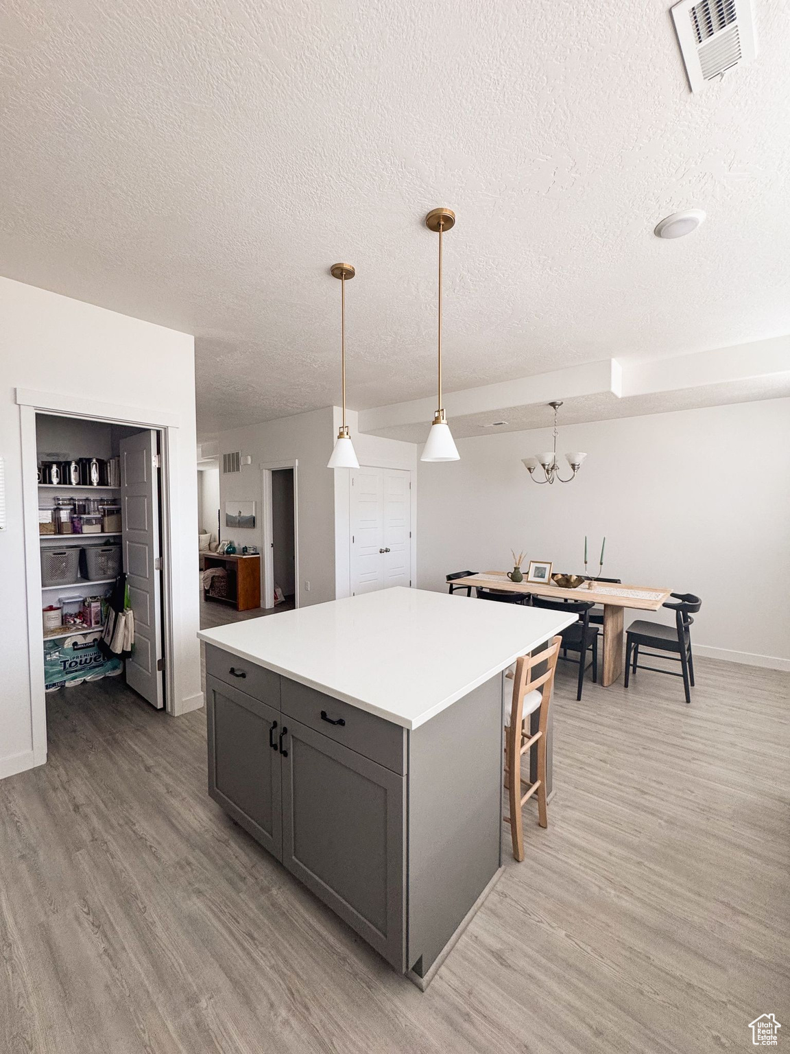 Kitchen with an inviting chandelier, light hardwood / wood-style flooring, decorative light fixtures, gray cabinets, and a kitchen island