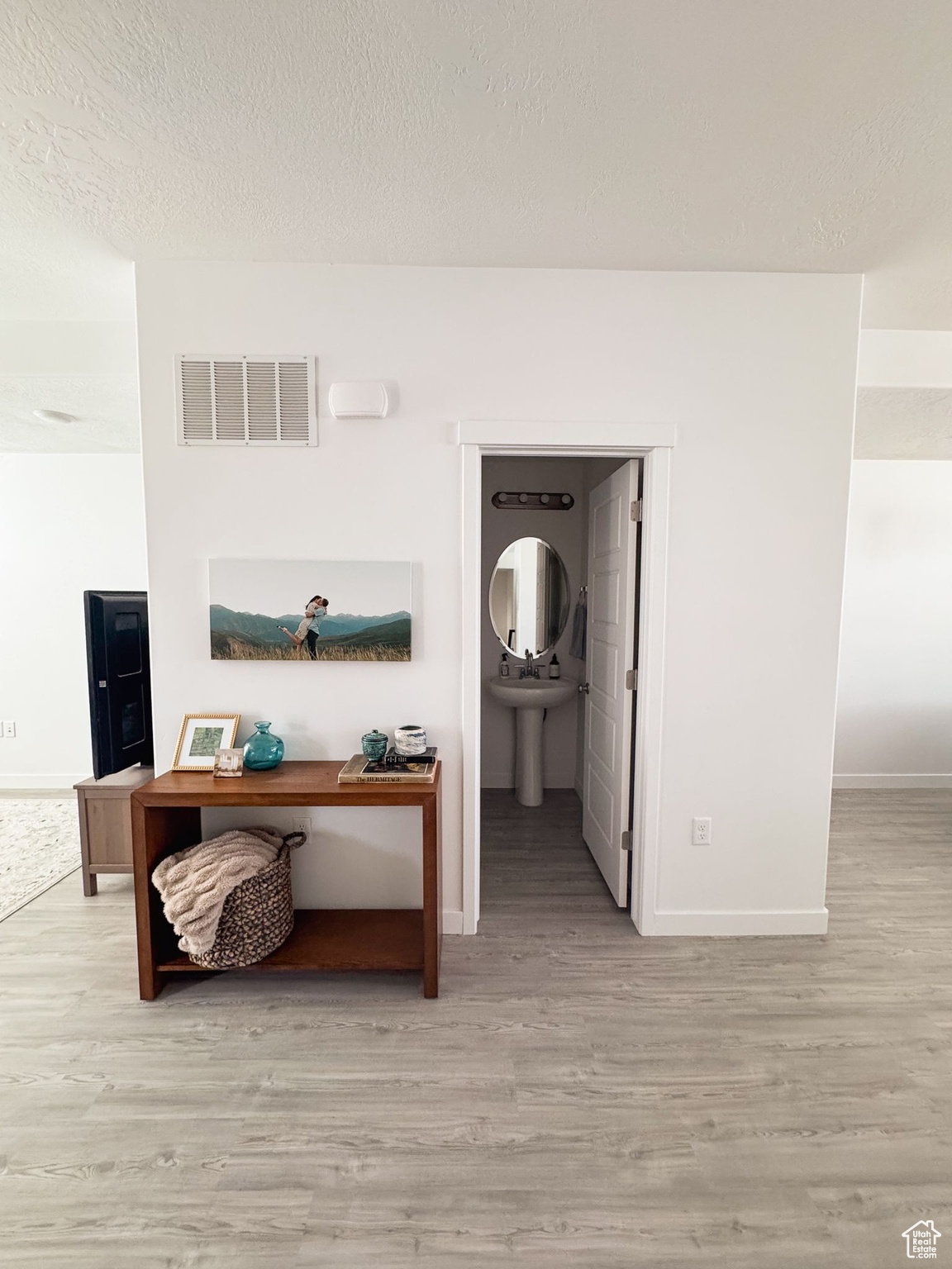 Hall with a textured ceiling and light hardwood / wood-style floors